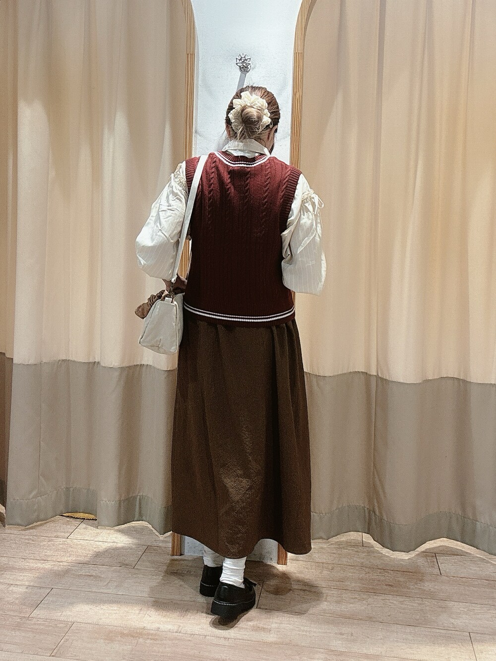 レッド系のベスト、ベージュ系のシャツ/ブラウス、ブラウン系のワンピースを着用したレディースの秋コーディネートの2枚目の写真