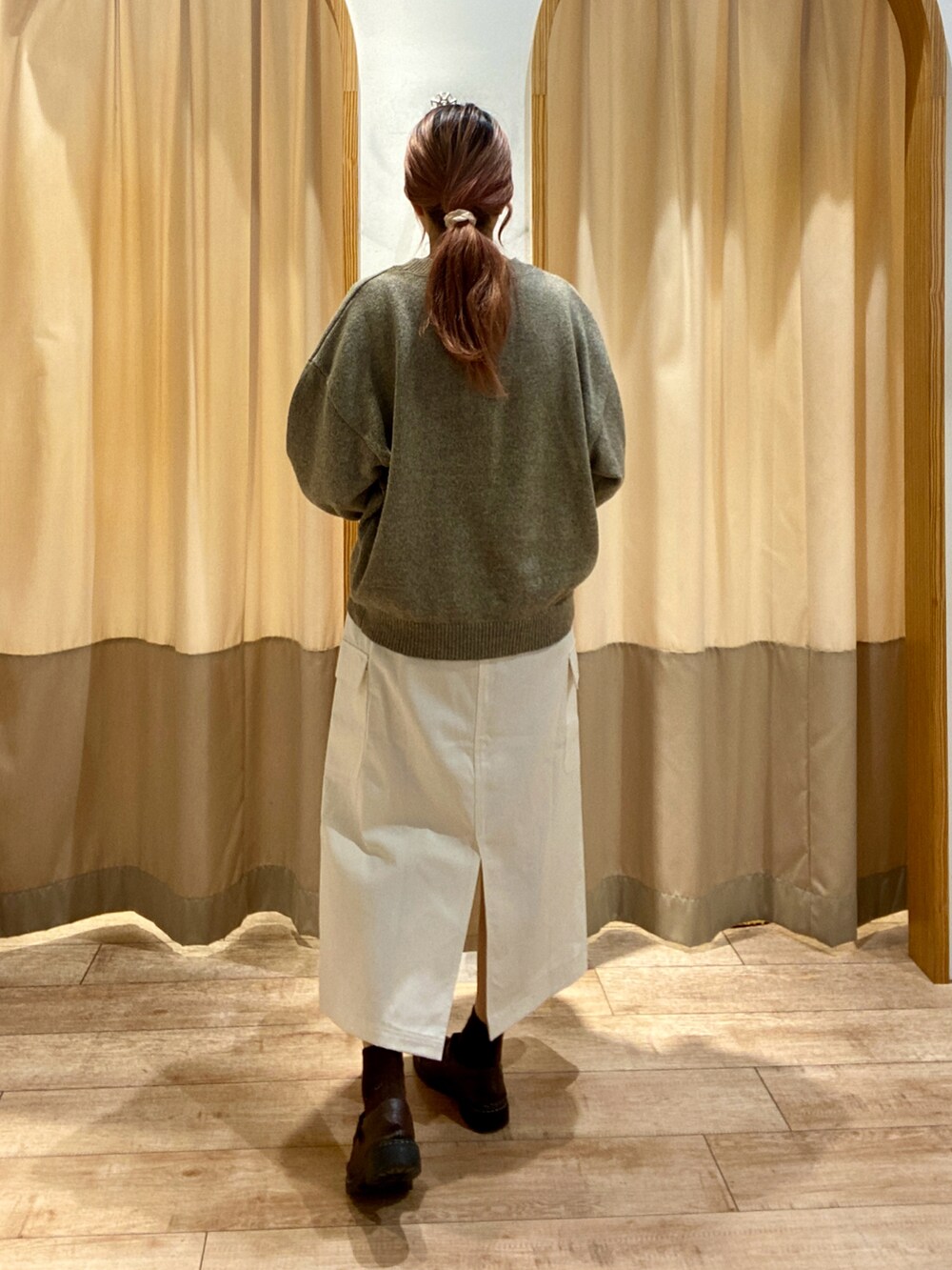 ブラウン系のニット/セーター、ブラウン系のハンドバッグ、ホワイト系のスカートを着用したレディースの秋コーディネートの3枚目の写真