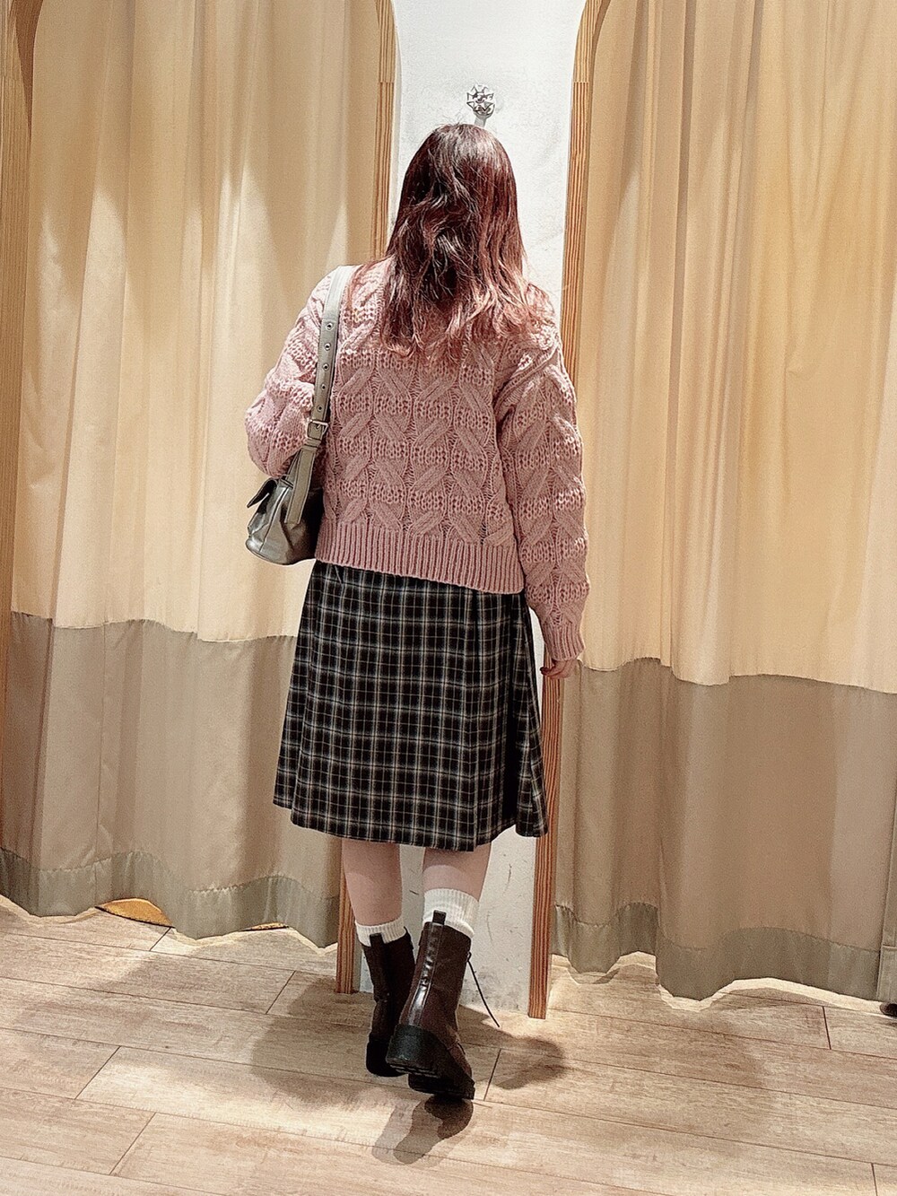 ピンク系のニット/セーター、グレー系のスカート、ブラウン系のブーツを着用したレディースの冬コーディネートの2枚目の写真