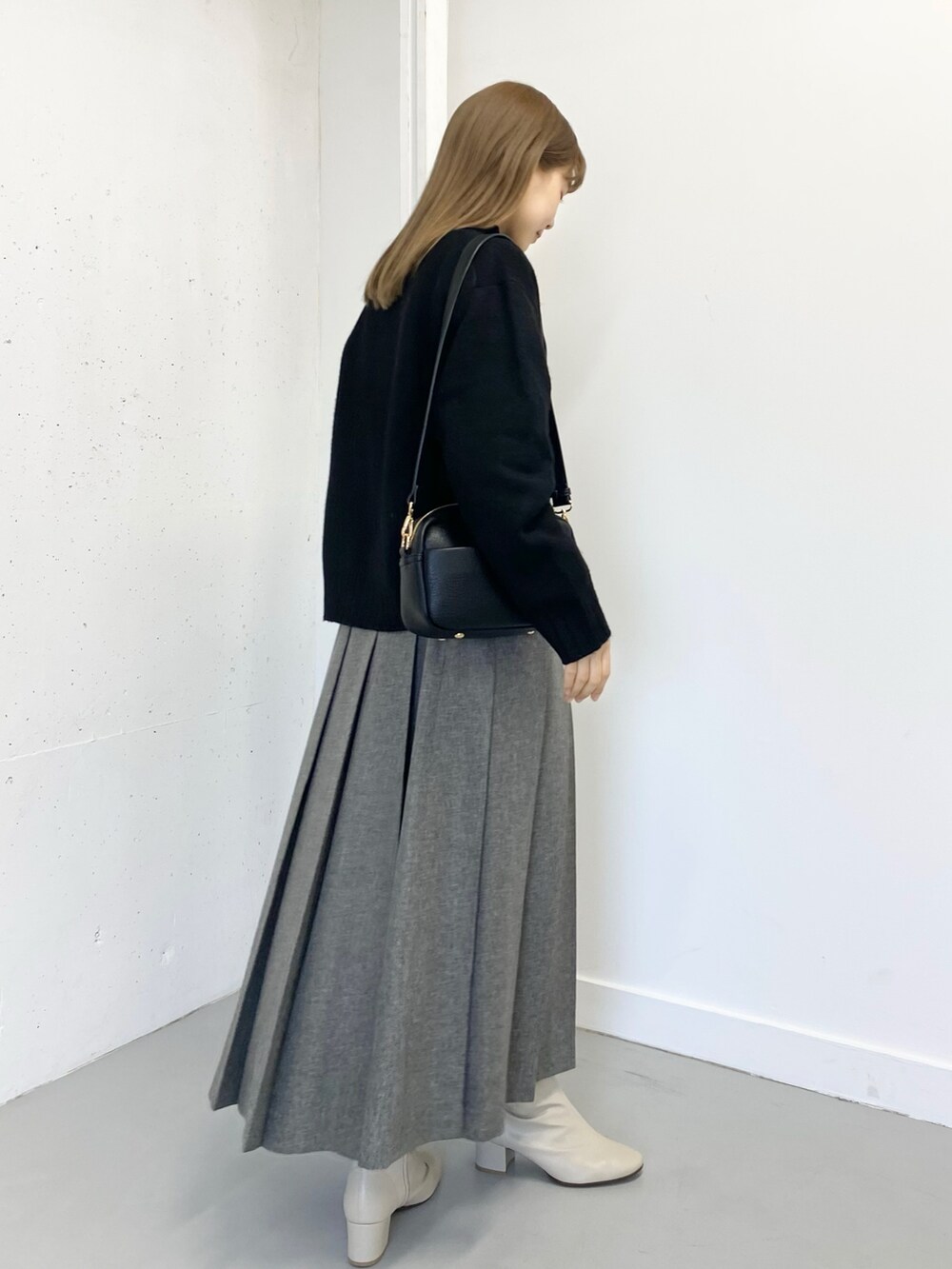 グレー系のスカート、ホワイト系のブーツ、ブラック系のショルダーバッグを着用したレディースの冬コーディネートの4枚目の写真