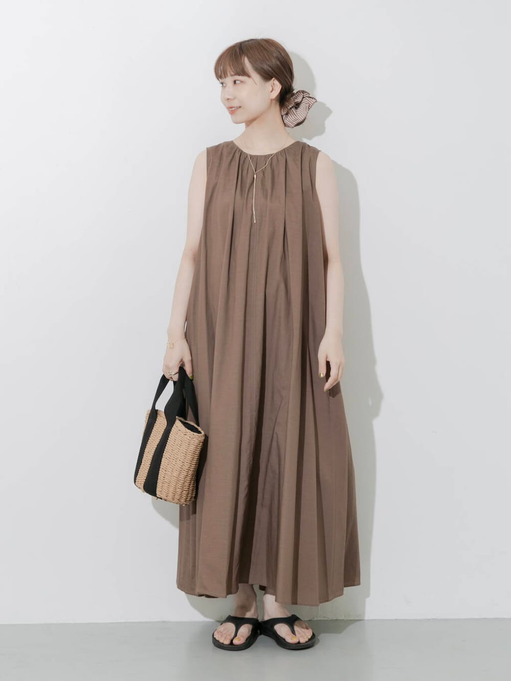 ブラック系のサンダル、ベージュ系のハンドバッグ、ゴールド系のネックレスを着用したレディースの夏コーディネートの2枚目の写真