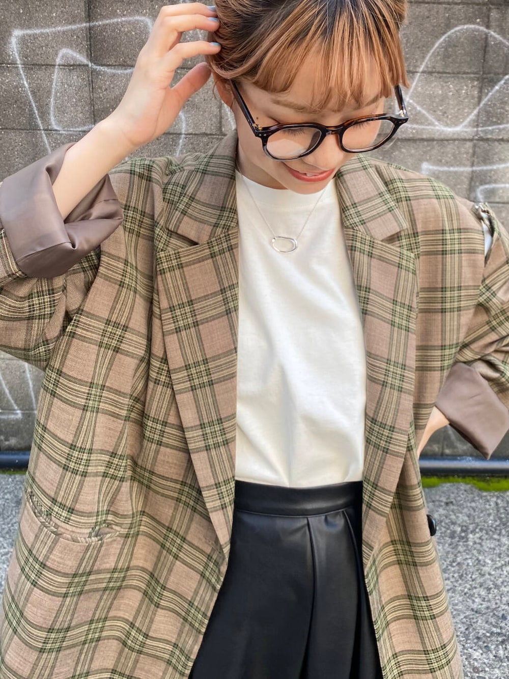 グリーン系のテーラードジャケット、ブラック系のブーツ、ブラック系のスカートを着用したレディースの秋コーディネートの7枚目の写真