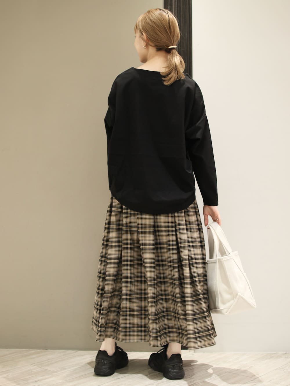 ベージュ系のトートバッグ、ベージュ系のスカート、ブラック系のTシャツ/カットソーを着用したレディースの冬コーディネートの3枚目の写真