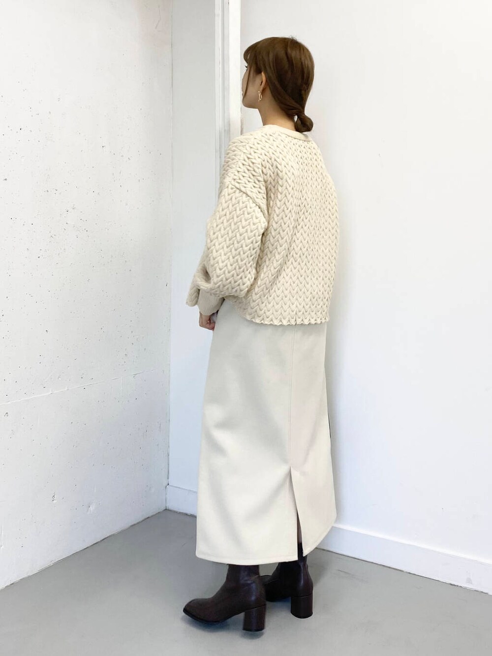 ブラウン系のハンドバッグ、ブラウン系のブーツ、ホワイト系のスカートを着用したレディースの冬コーディネートの5枚目の写真