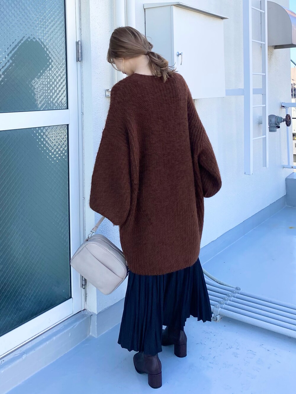 ベージュ系のショルダーバッグ、ブラウン系のブーツ、ブラック系のスカートを着用したレディースの冬コーディネートの4枚目の写真