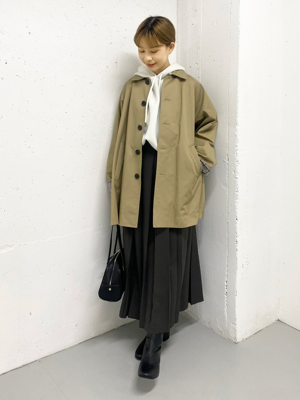 グレー系のスカート、ブラック系のブーツ、ベージュ系のステンカラーコートを着用したレディースの秋コーディネートの3枚目の写真