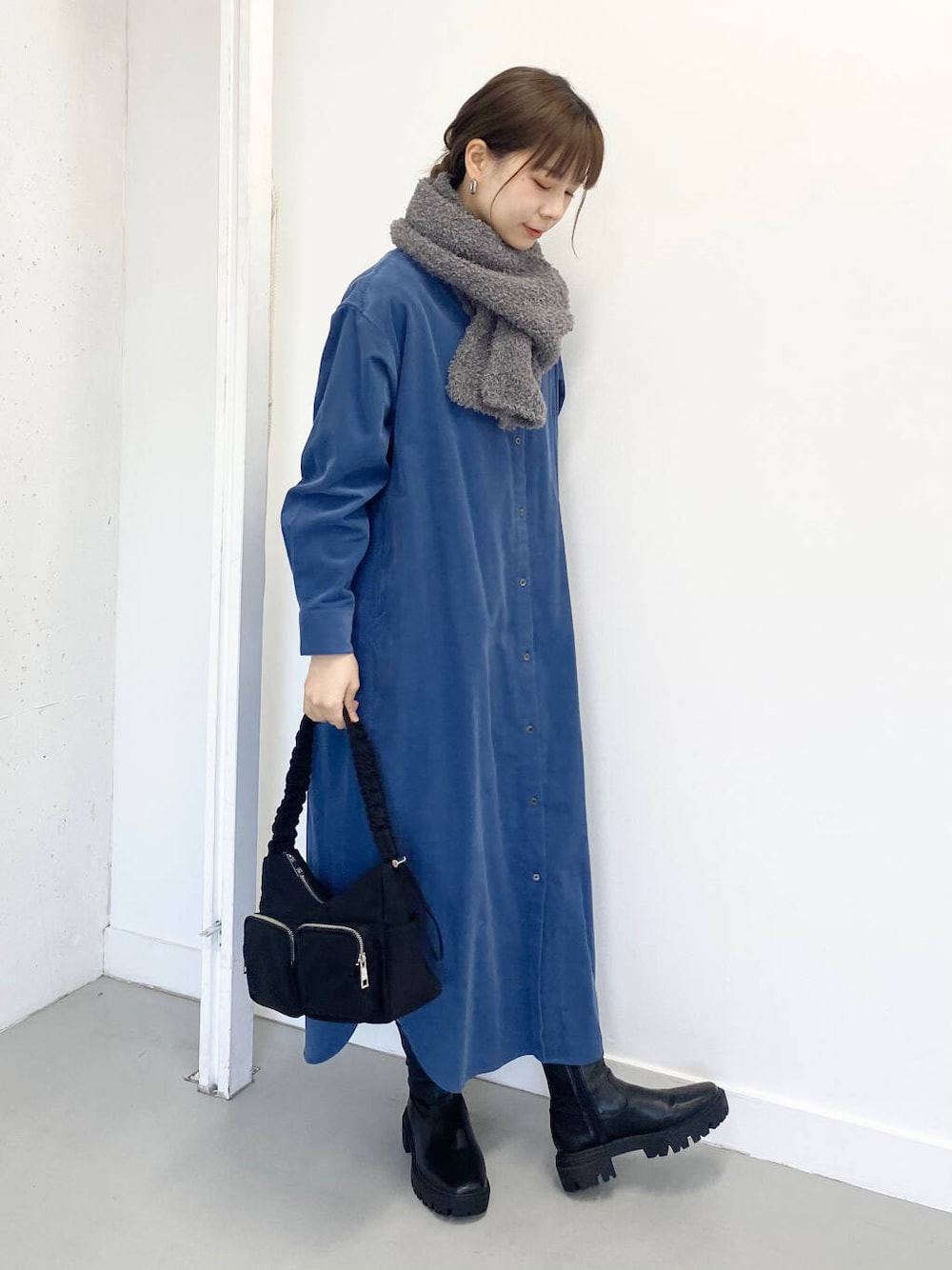 ブラック系のショルダーバッグ、ブルー系のワンピース、ブラック系のブーツを着用したレディースの冬コーディネートの2枚目の写真
