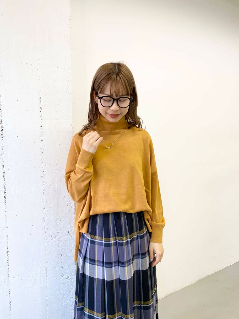 イエロー系のニット/セーター、ブラック系のブーツ、ブラック系のスカートを着用したレディースの秋コーディネートの5枚目の写真