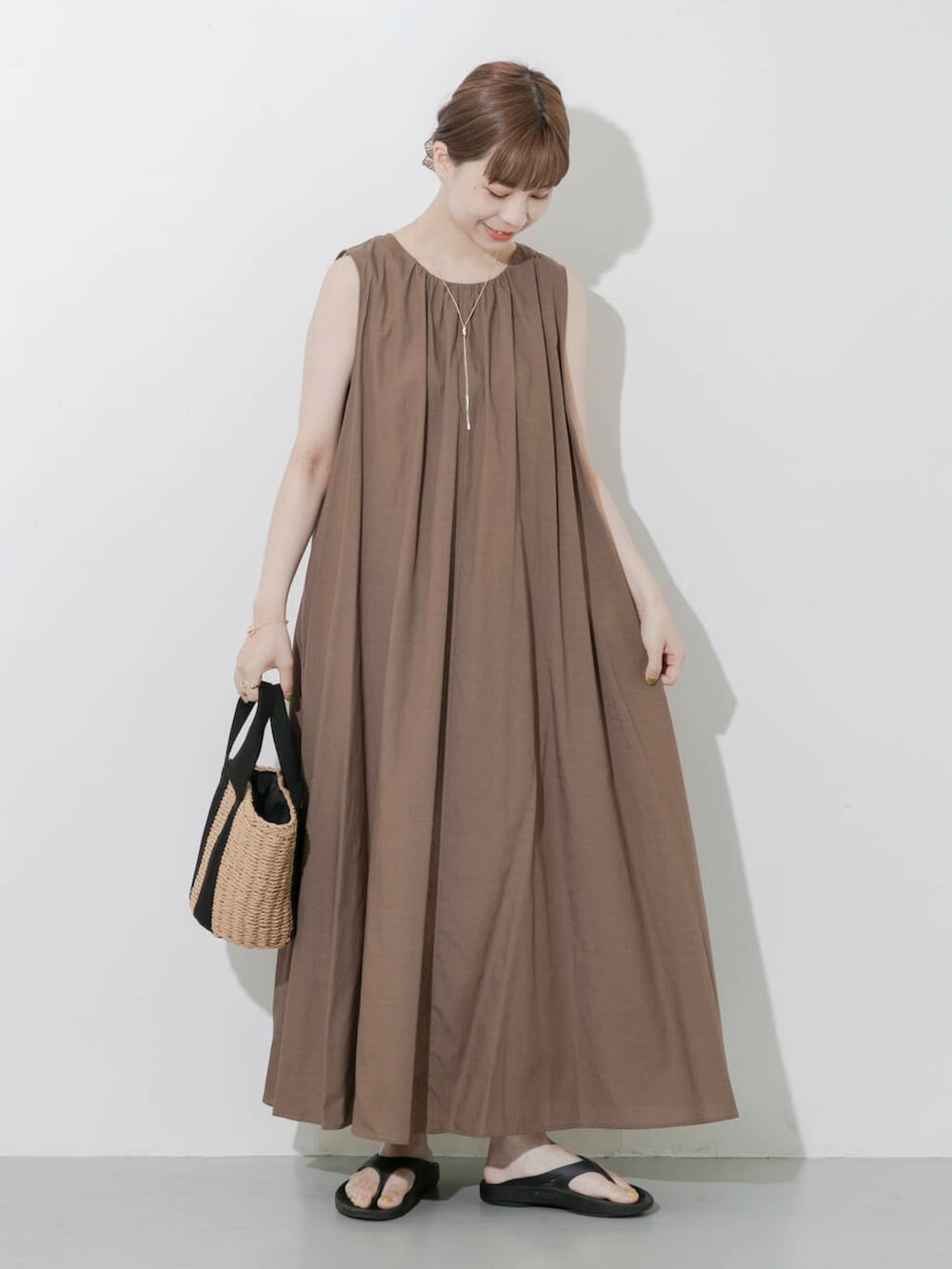 ブラック系のサンダル、ベージュ系のハンドバッグ、ゴールド系のネックレスを着用したレディースの夏コーディネートの5枚目の写真