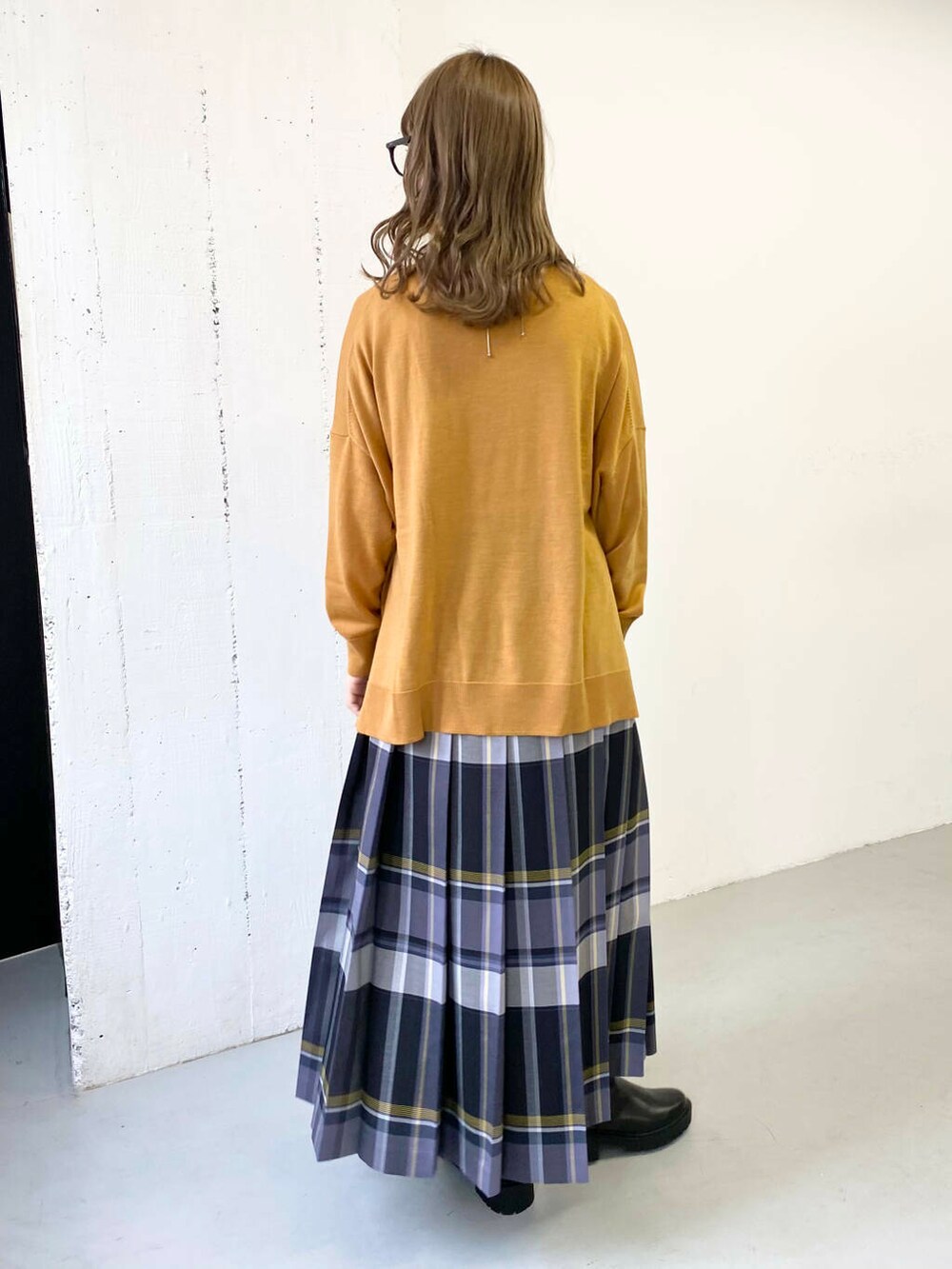 イエロー系のニット/セーター、ブラック系のブーツ、ブラック系のスカートを着用したレディースの秋コーディネートの3枚目の写真