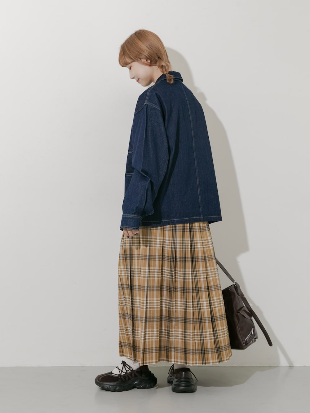 ブラウン系のスニーカー、ブルー系のカバーオール、イエロー系のスカートを着用したレディースの秋コーディネートの6枚目の写真