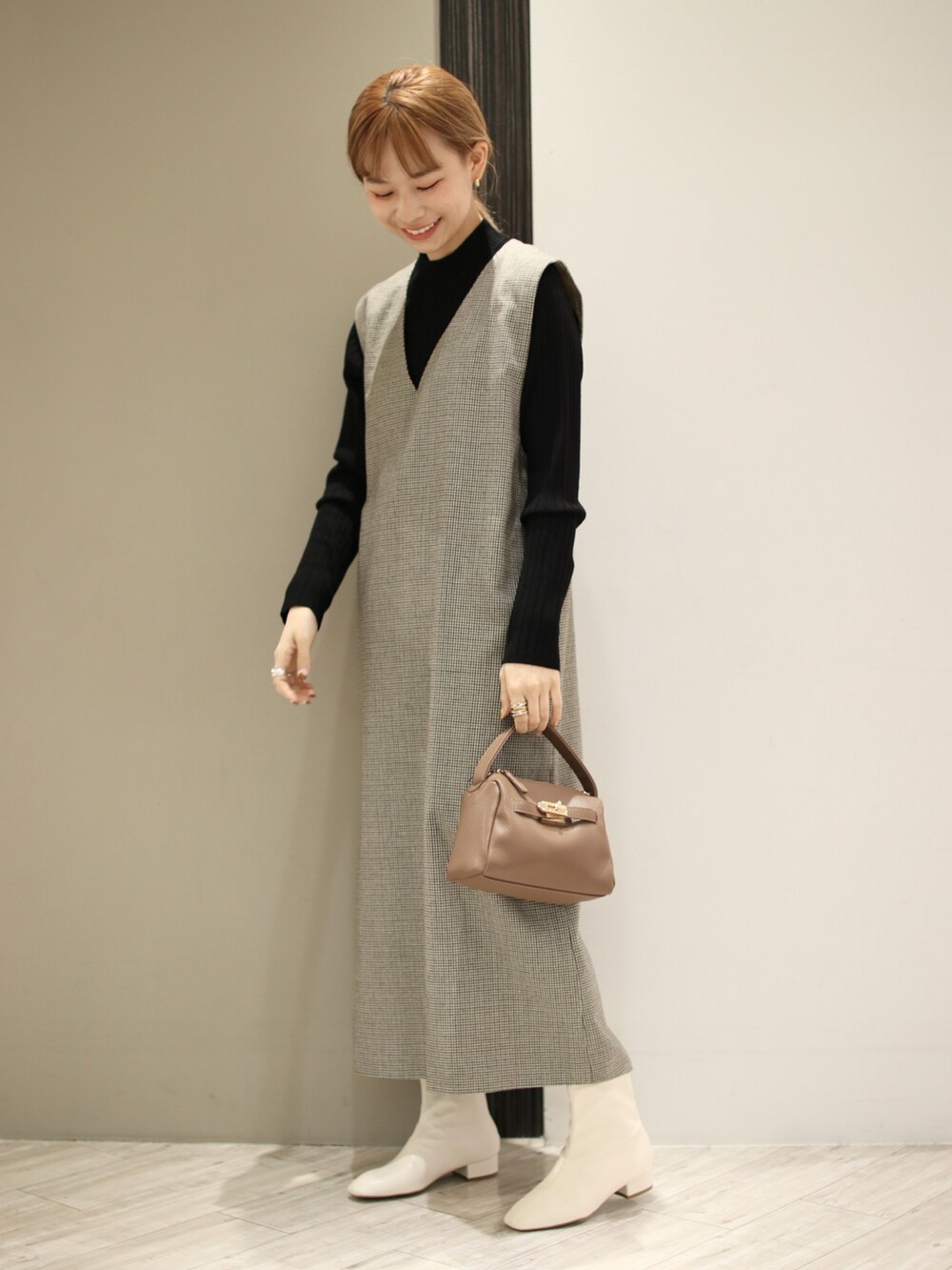 ブラウン系のハンドバッグ、ホワイト系のブーツ、ベージュ系のワンピースを着用したレディースの冬コーディネートの3枚目の写真