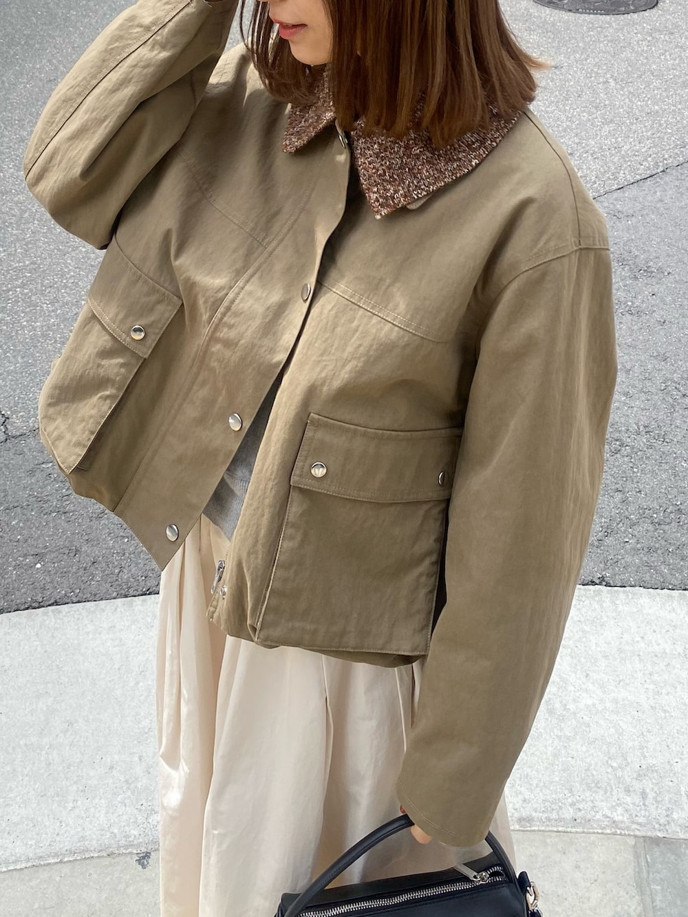 グリーン系のブルゾン、ホワイト系のスカート、ブラウン系のメガネを着用したレディースの春コーディネートの5枚目の写真