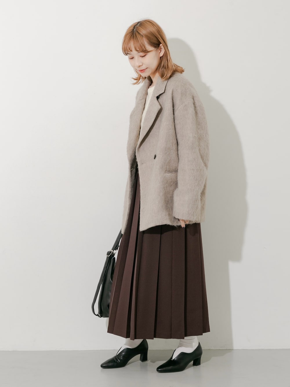 ブラウン系のスカート、ブラウン系のその他アウター、ホワイト系のTシャツ/カットソーを着用したレディースの秋コーディネートの3枚目の写真