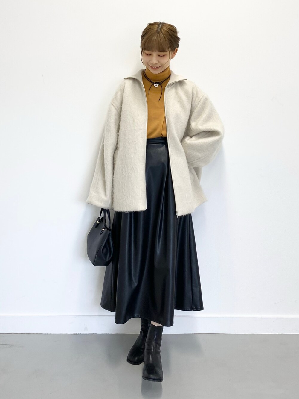 ブラック系のショルダーバッグ、ブラック系のブーツ、ブラック系のスカートを着用したレディースの冬コーディネートの5枚目の写真