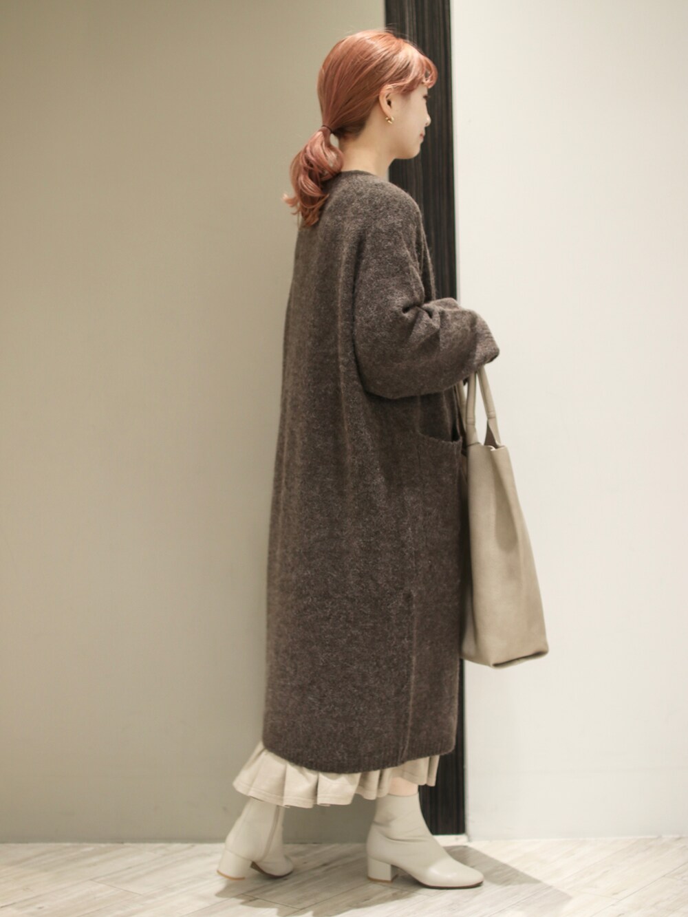 グレー系のスカート、ホワイト系のブーツ、グレー系のトートバッグを着用したレディースの秋コーディネートの4枚目の写真