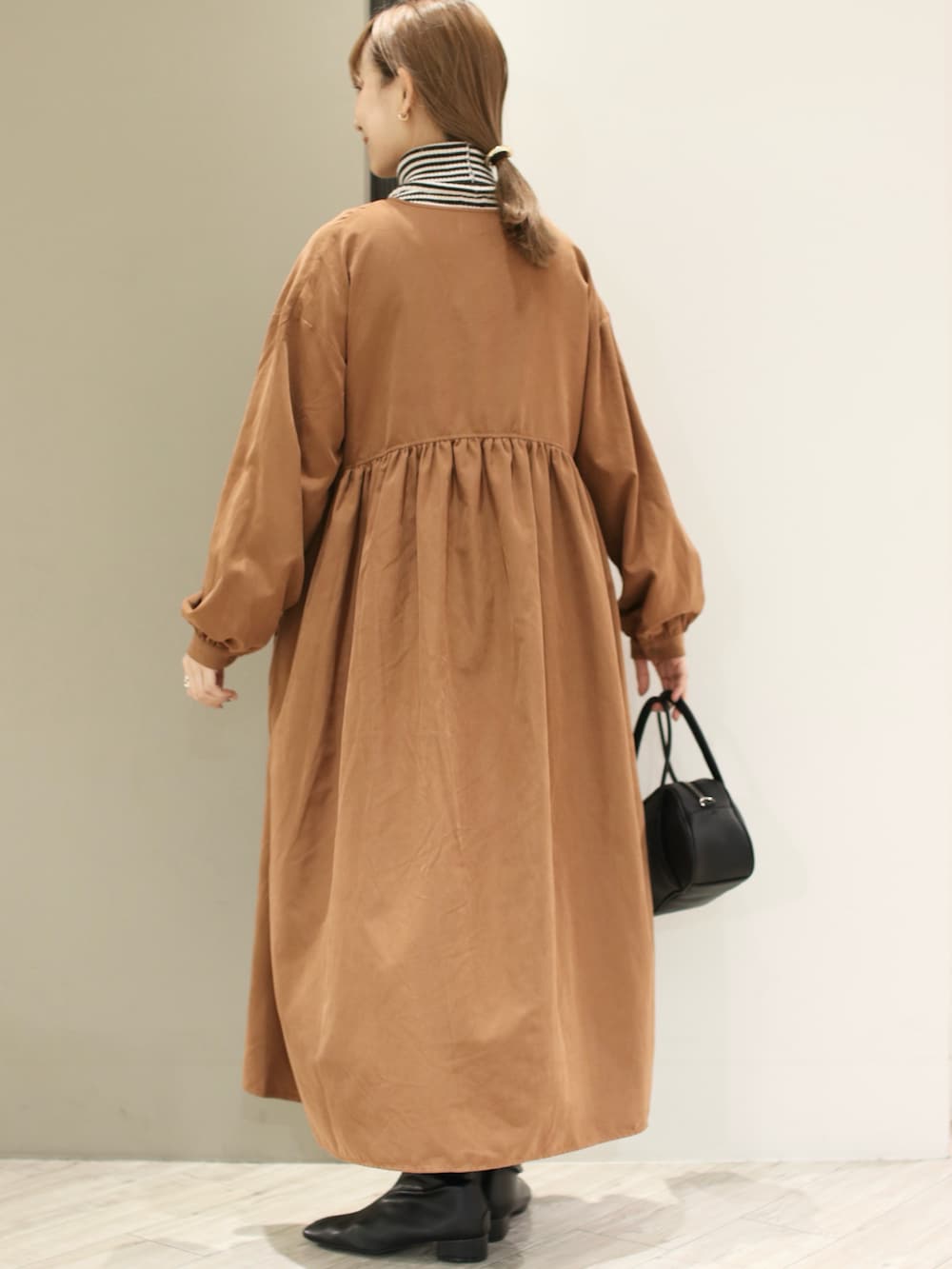 ブラック系のショルダーバッグ、イエロー系のワンピース、グレー系のニット/セーターを着用したレディースの冬コーディネートの3枚目の写真