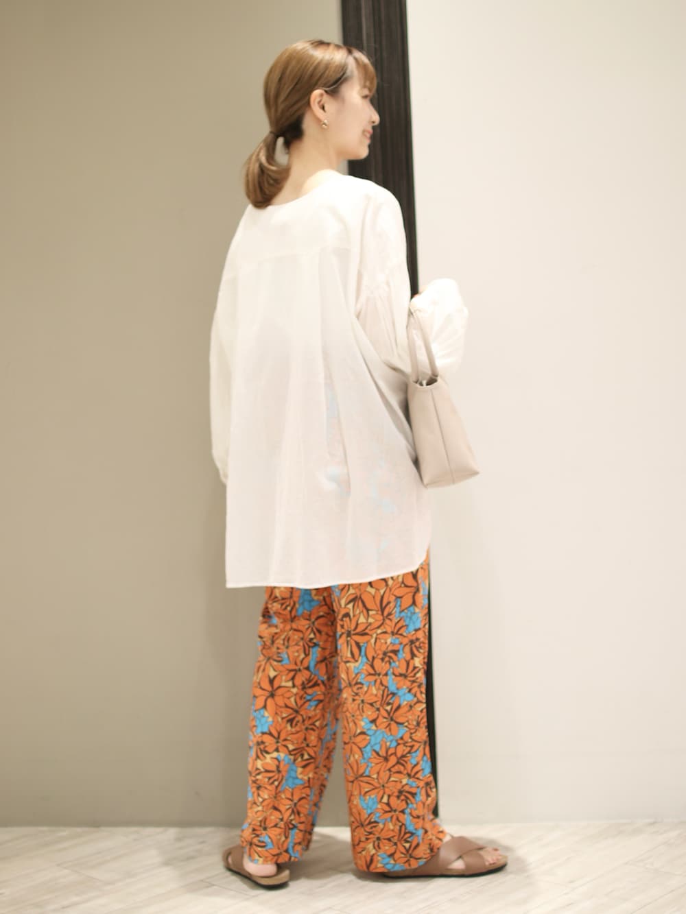 オレンジ系のその他パンツ、ホワイト系のシャツ/ブラウス、ベージュ系のハンドバッグを着用したレディースの夏コーディネートの3枚目の写真