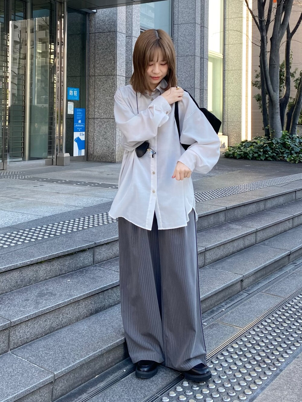 ブラック系のトートバッグ、ブラック系のローファー、グレー系のその他パンツを着用したレディースの春コーディネートの2枚目の写真