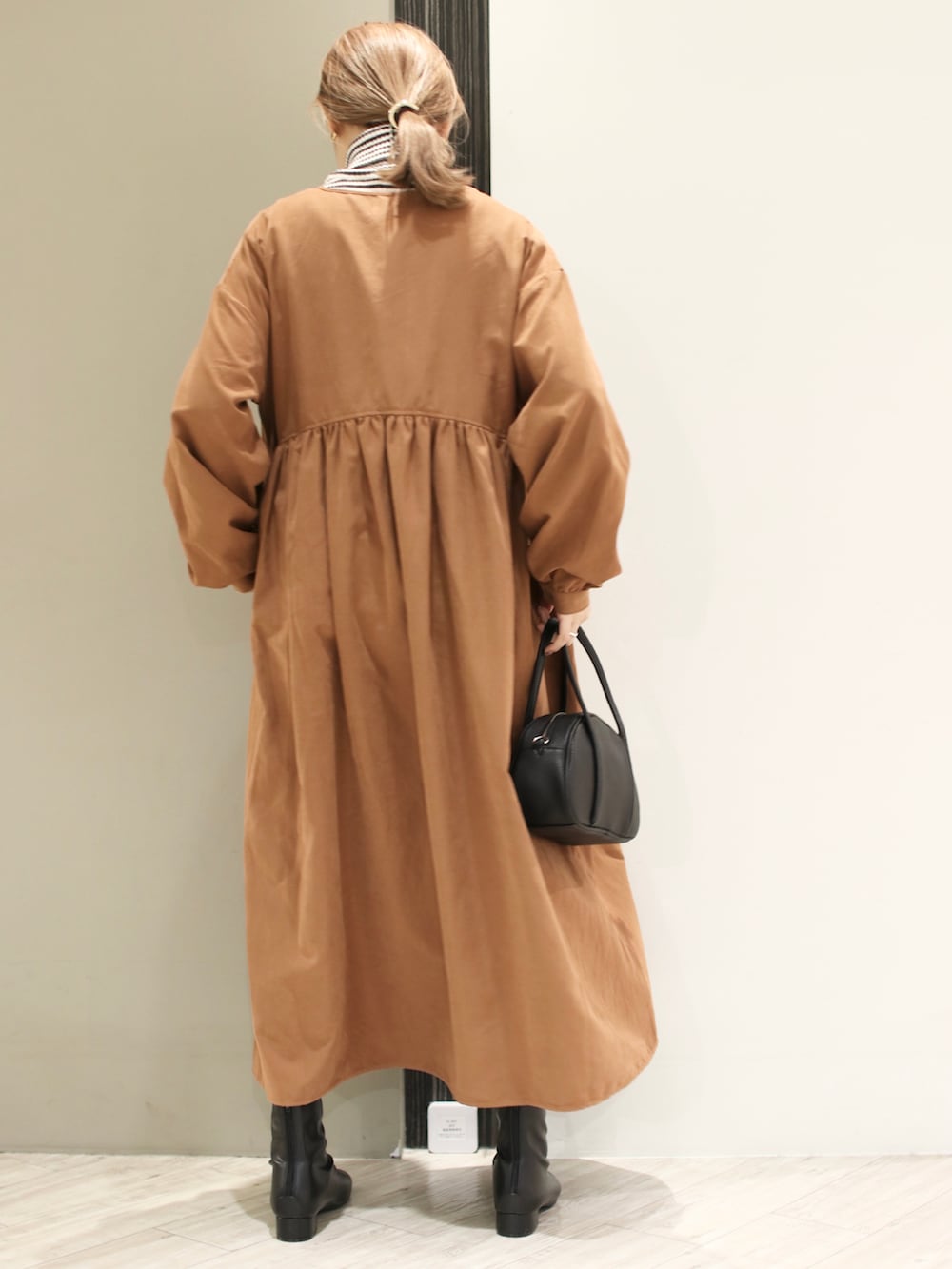 ブラック系のショルダーバッグ、イエロー系のワンピース、グレー系のニット/セーターを着用したレディースの冬コーディネートの4枚目の写真