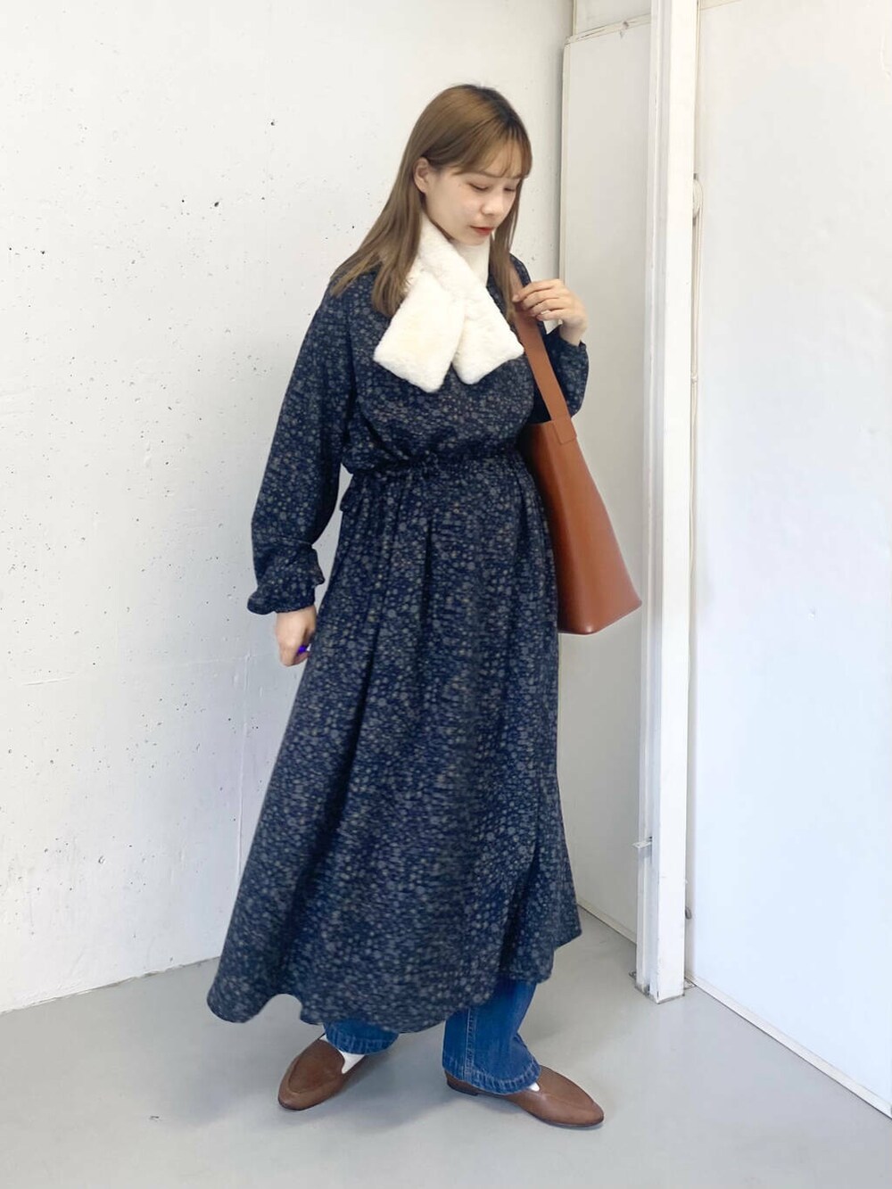 ブラウン系のスリッポン、ブルー系のデニムパンツ、ブラウン系のトートバッグを着用したレディースの秋コーディネートの3枚目の写真