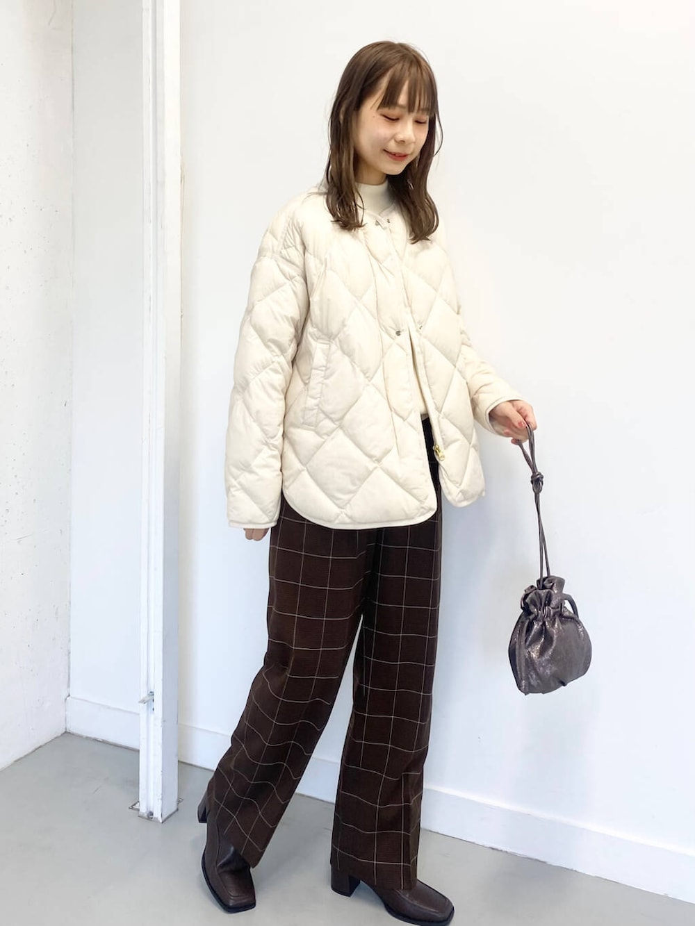 ホワイト系のダウンジャケット/コート、ホワイト系のニット/セーター、ブラウン系のブーツを着用したレディースの冬コーディネートの6枚目の写真