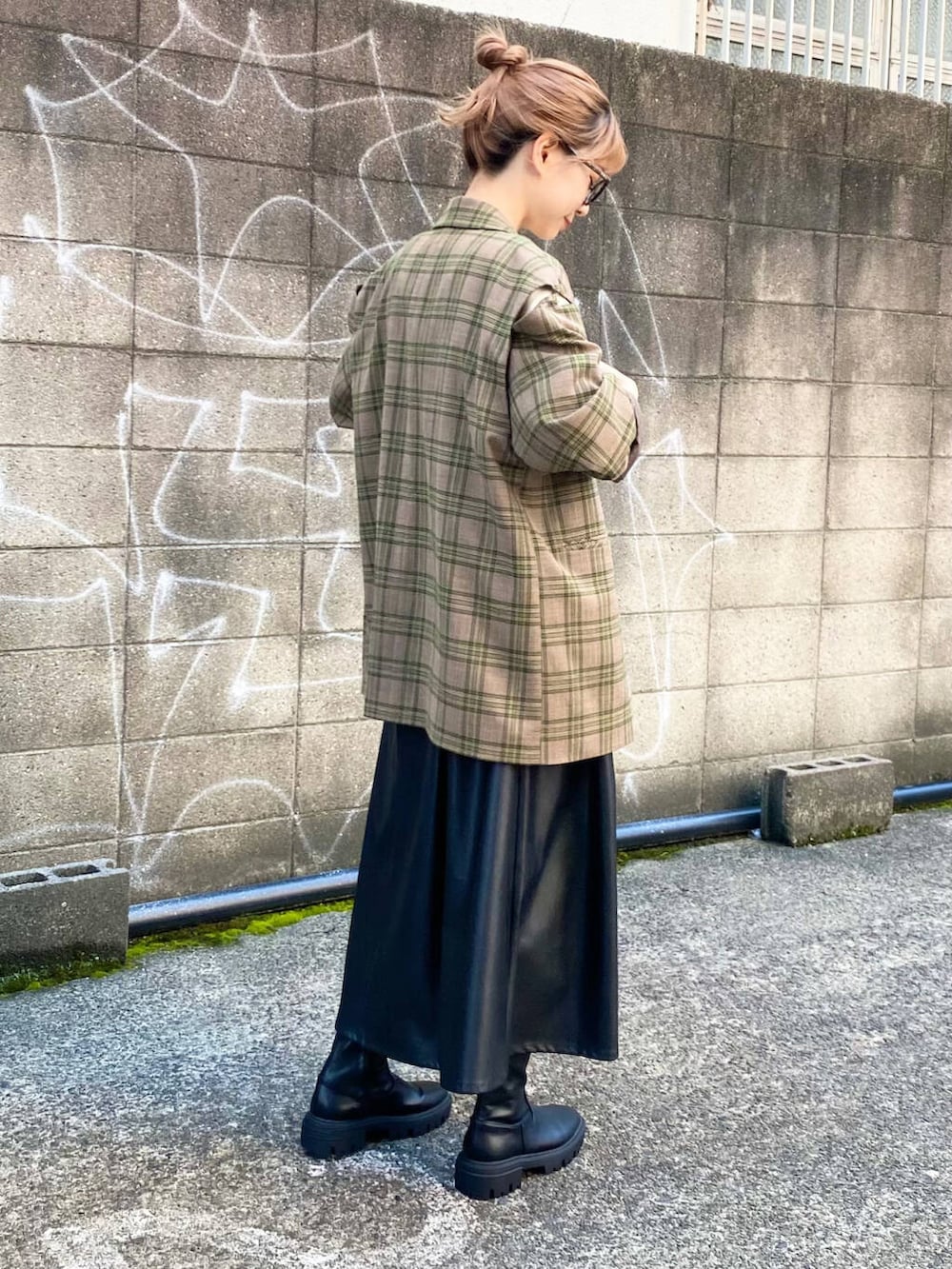 グリーン系のテーラードジャケット、ブラック系のブーツ、ブラック系のスカートを着用したレディースの秋コーディネートの4枚目の写真