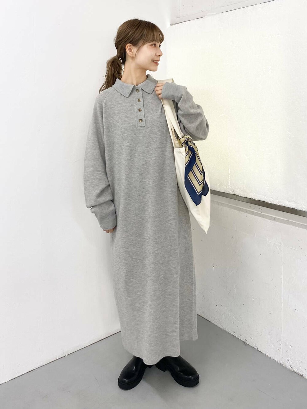 ブラック系のブーツ、ホワイト系のトートバッグ、グレー系のワンピースを着用したレディースの秋コーディネートの2枚目の写真