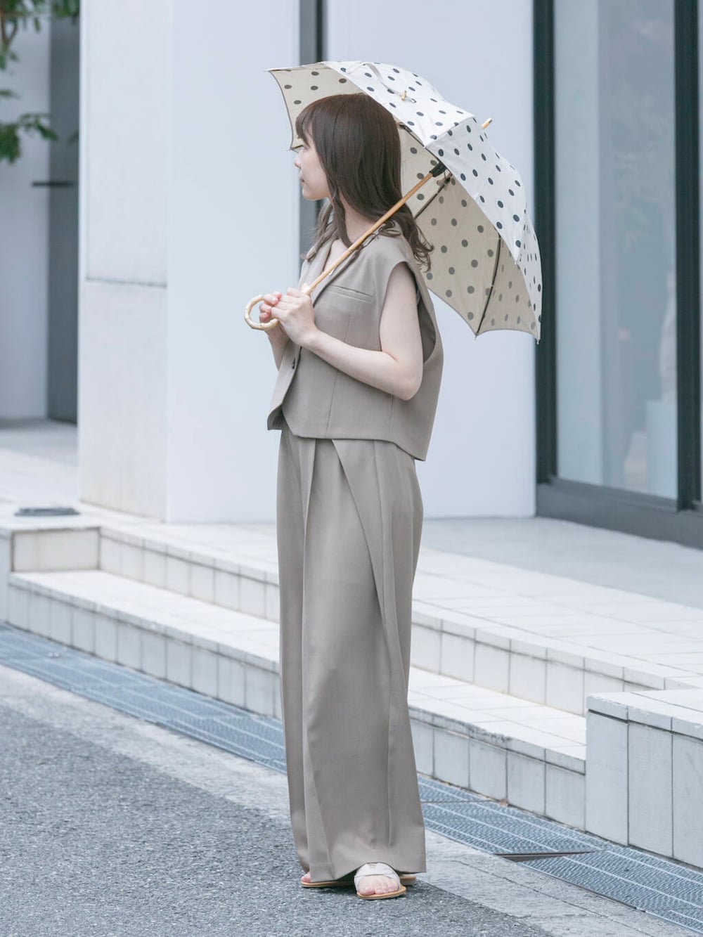 ベージュ系のその他パンツ、ベージュ系のその他アウター、ホワイト系の長傘を着用したレディースの春コーディネートの2枚目の写真