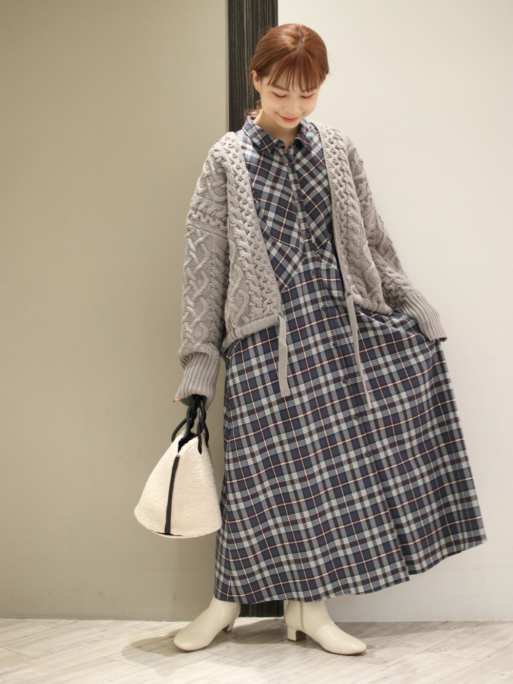 ホワイト系のハンドバッグ、グレー系のワンピース、グレー系のニット/セーターを着用したレディースの秋コーディネートの2枚目の写真