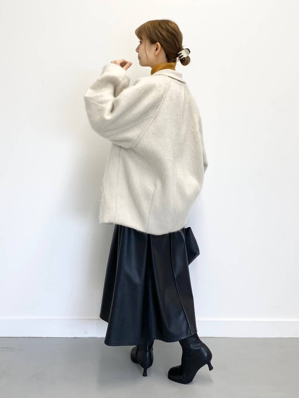 イエロー系のニット/セーター、ブラック系のショルダーバッグ、ブラック系のブーツを着用したレディースの冬コーディネートの2枚目の写真