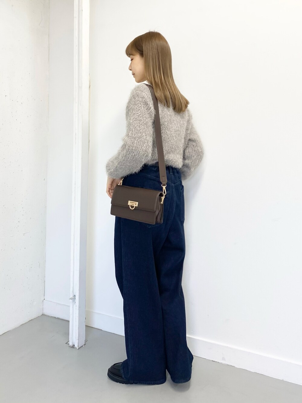 ブラック系のローファー、ブルー系のデニムパンツ、グレー系のニット/セーターを着用したレディースの冬コーディネートの3枚目の写真