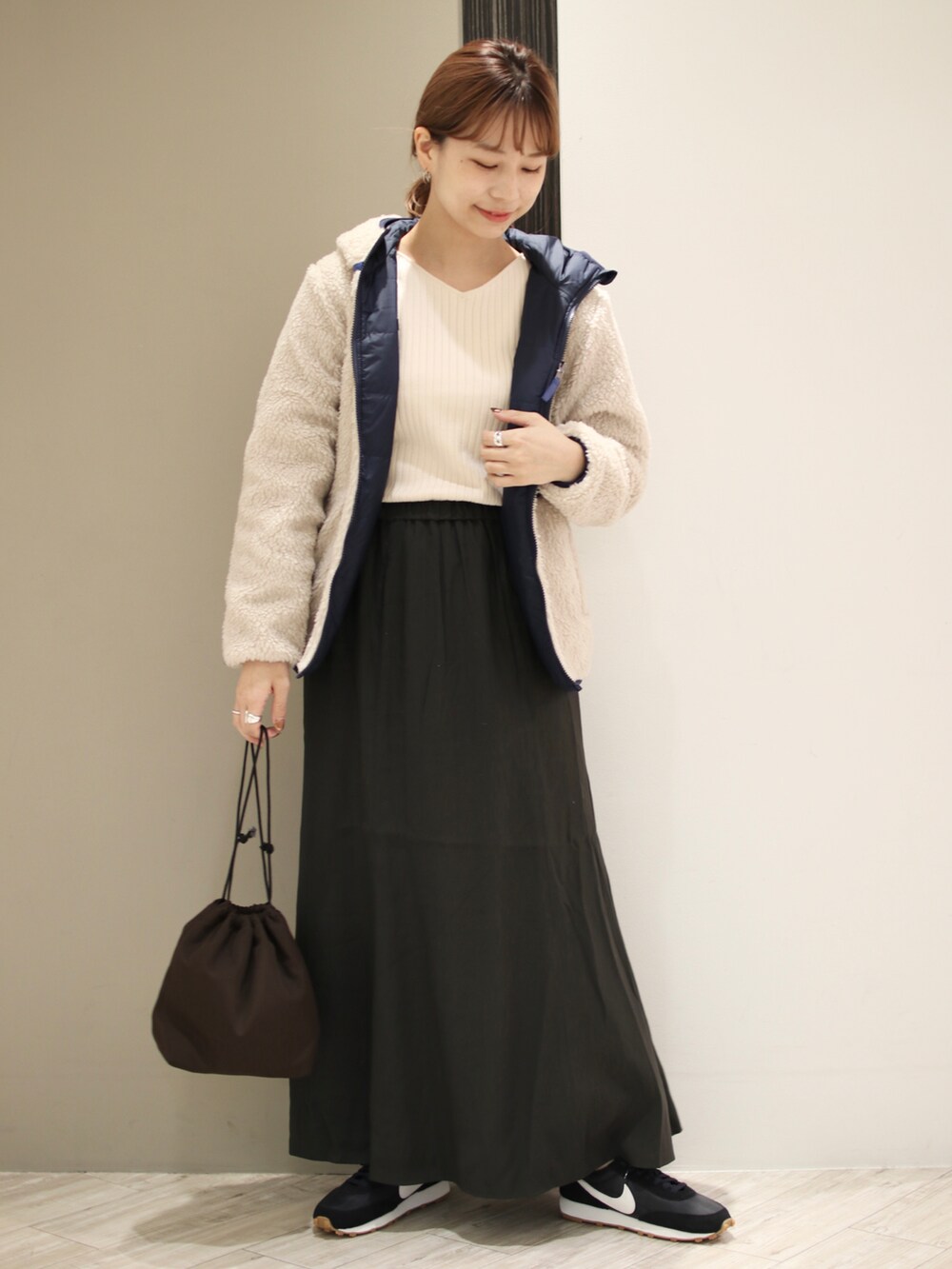 ブラック系のスニーカー、グレー系のスカート、ブラウン系のショルダーバッグを着用したレディースの秋コーディネートの2枚目の写真