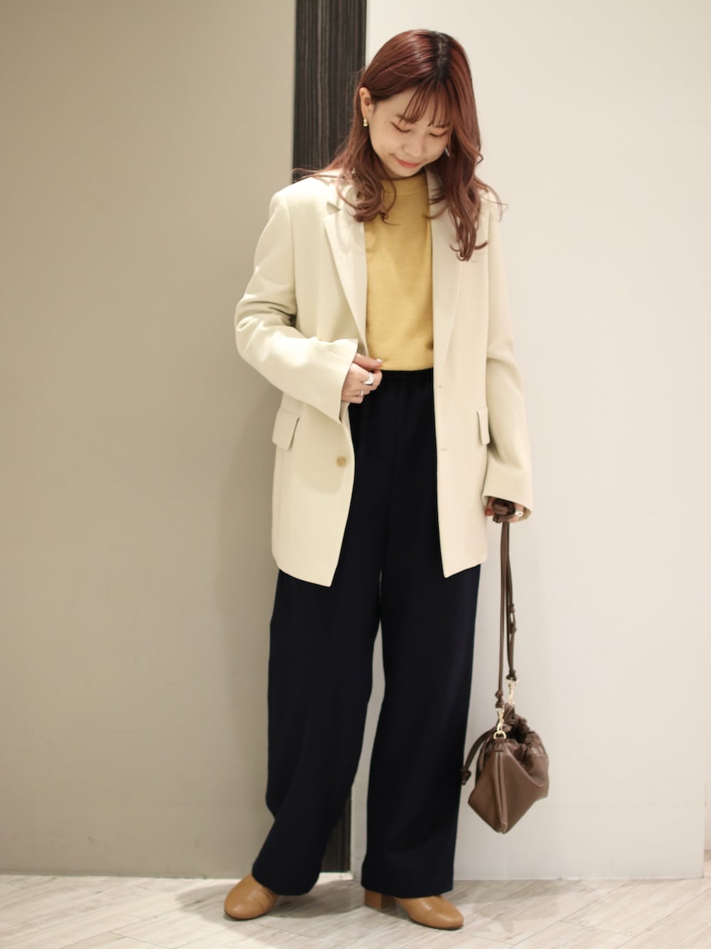 イエロー系のニット/セーター、ブラウン系のハンドバッグ、イエロー系のブーツを着用したレディースの冬コーディネートの2枚目の写真