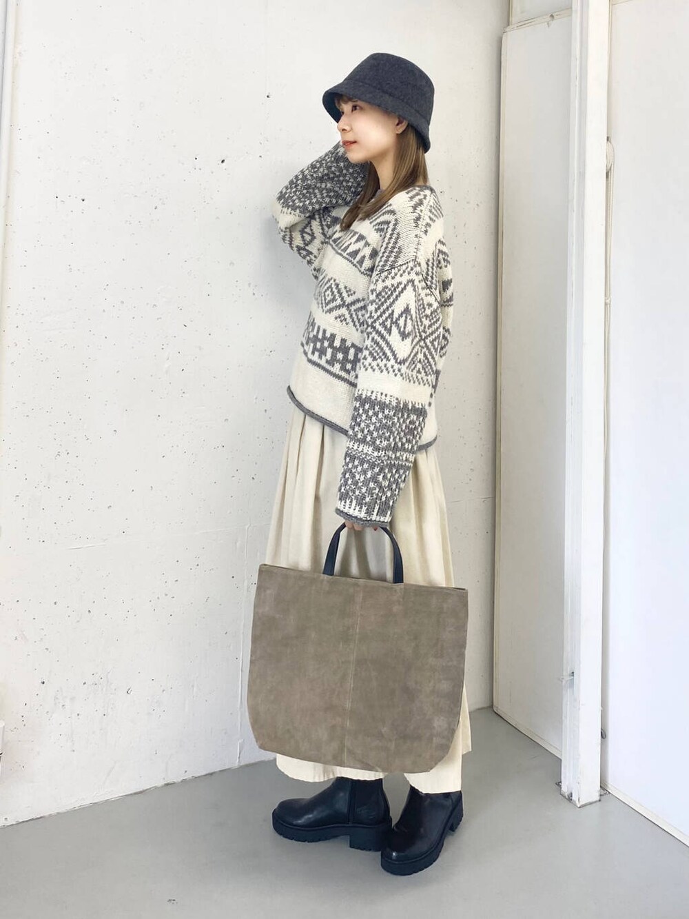 ベージュ系のトートバッグ、ブラック系のブーツ、ホワイト系のスカートを着用したレディースの秋コーディネートの3枚目の写真