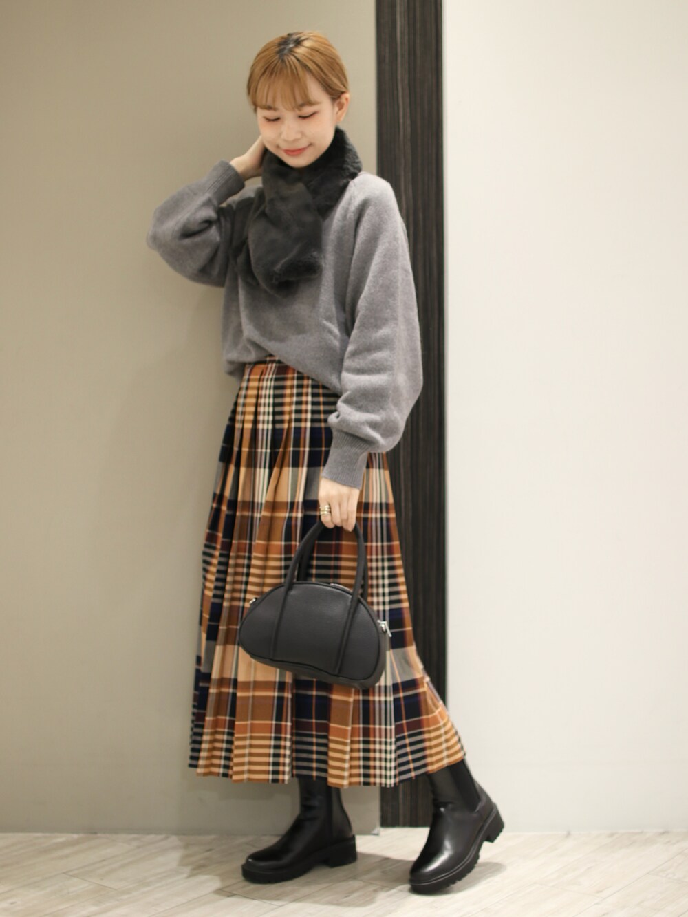 グレー系のニット/セーター、オレンジ系のスカート、ブラック系のショルダーバッグを着用したレディースの秋コーディネートの2枚目の写真