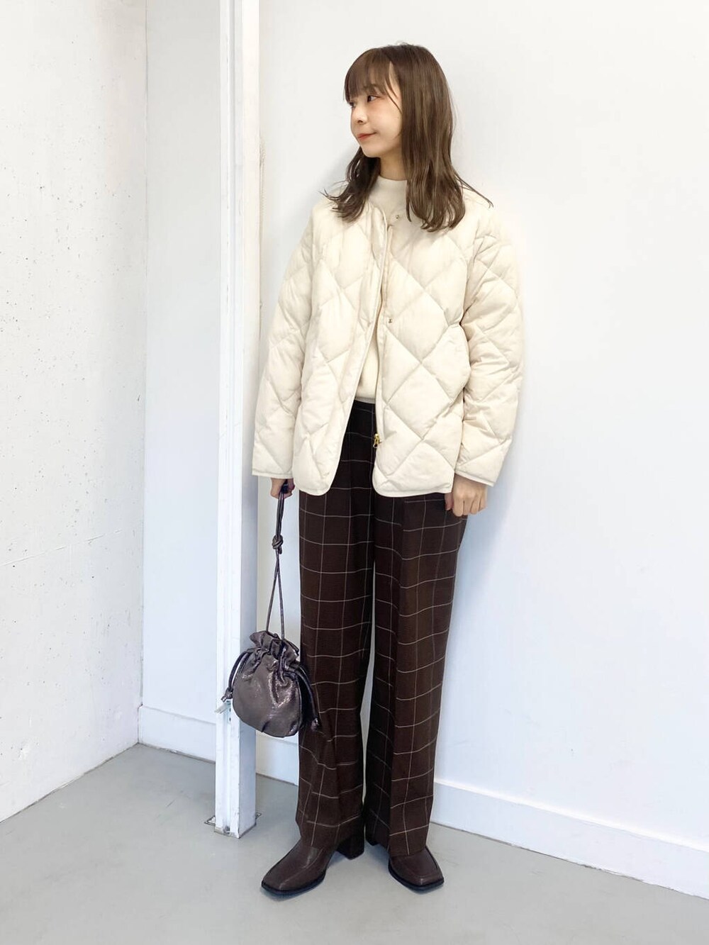 ホワイト系のダウンジャケット/コート、ホワイト系のニット/セーター、ブラウン系のブーツを着用したレディースの冬コーディネートの5枚目の写真