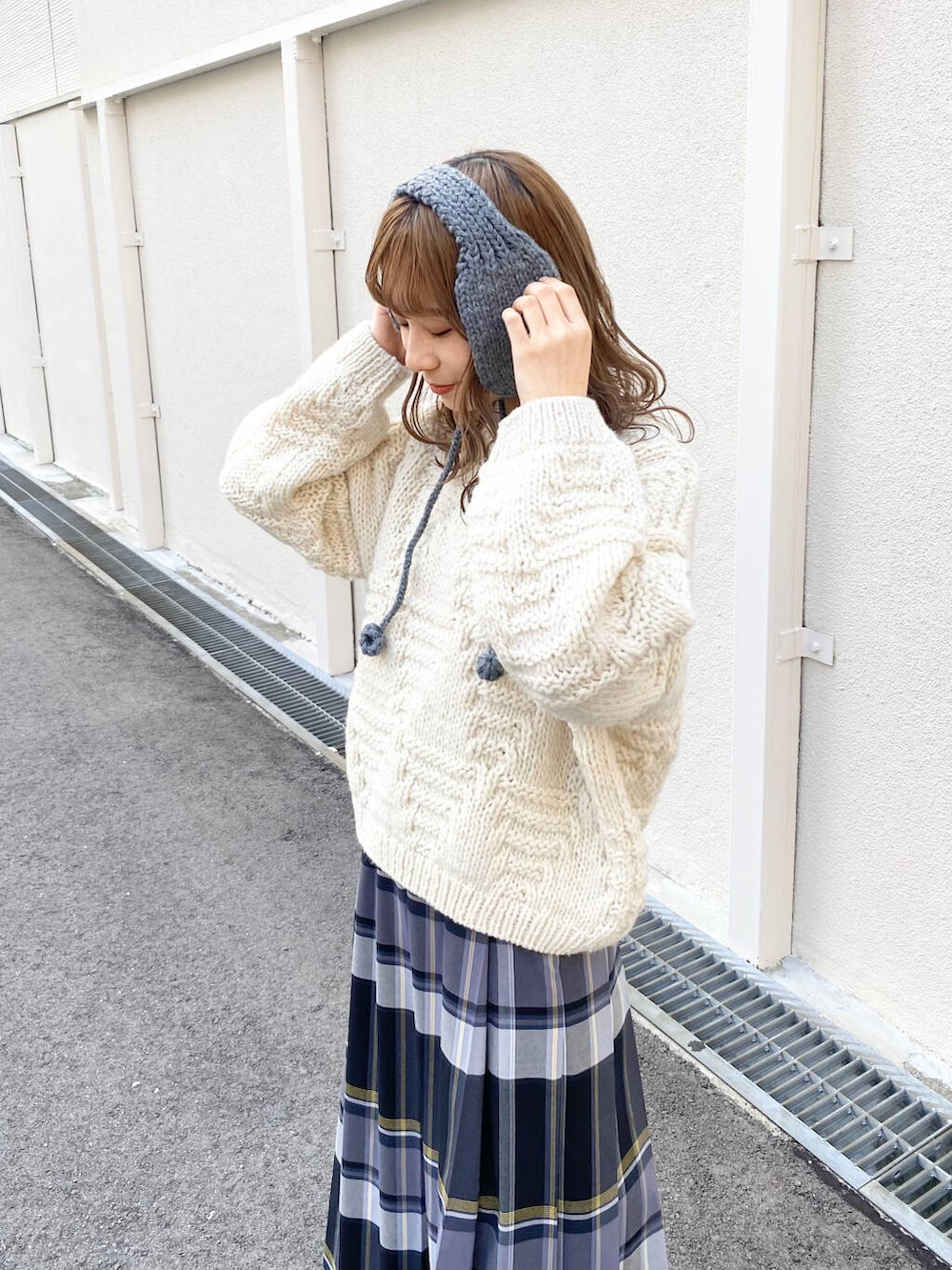 ホワイト系のニット/セーター、ブラウン系のブーツ、ブラック系のスカートを着用したレディースの冬コーディネートの2枚目の写真