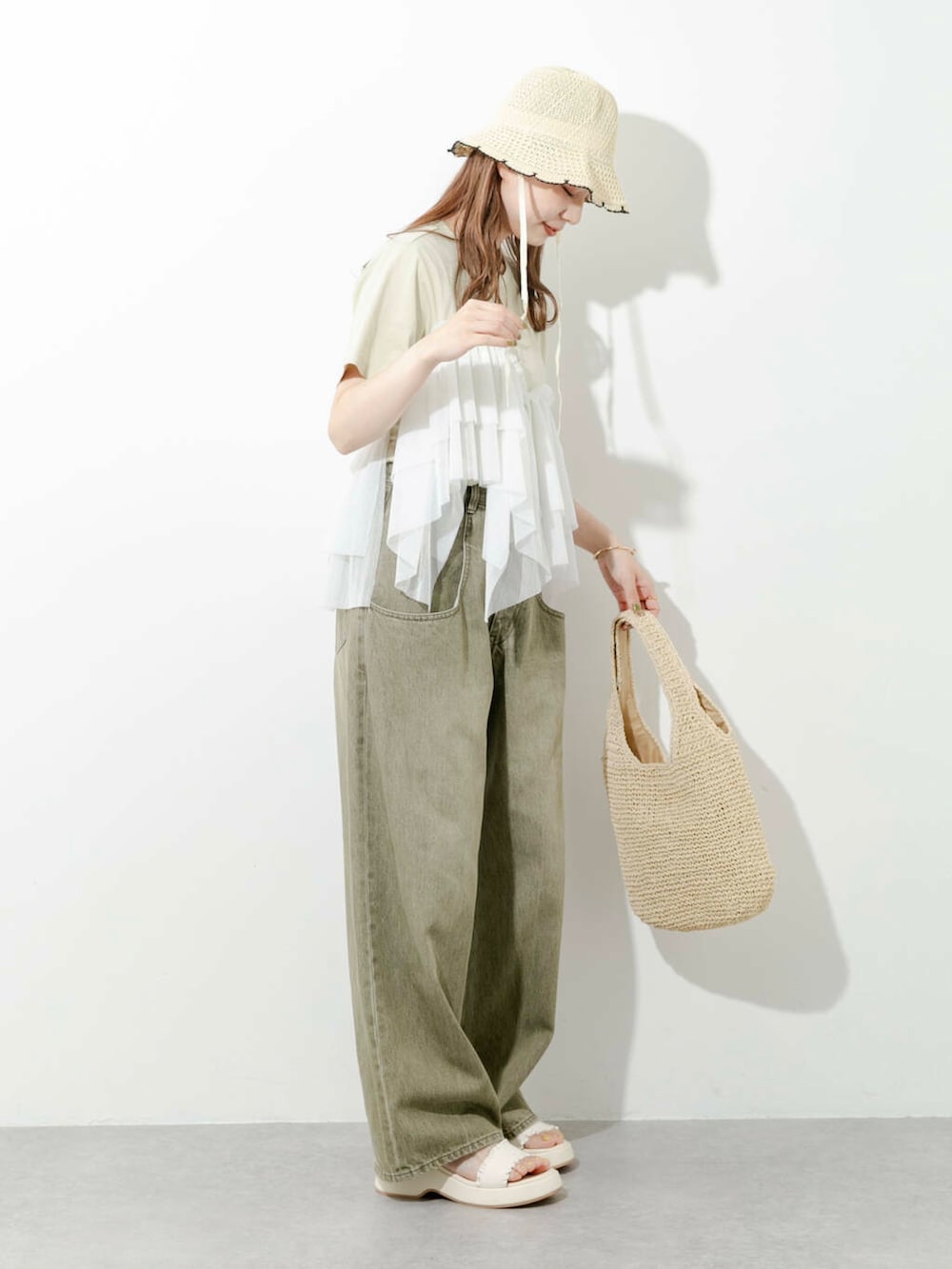 ベージュ系のトートバッグ、グリーン系のTシャツ/カットソー、ホワイト系のサンダルを着用したレディースの夏コーディネートの2枚目の写真