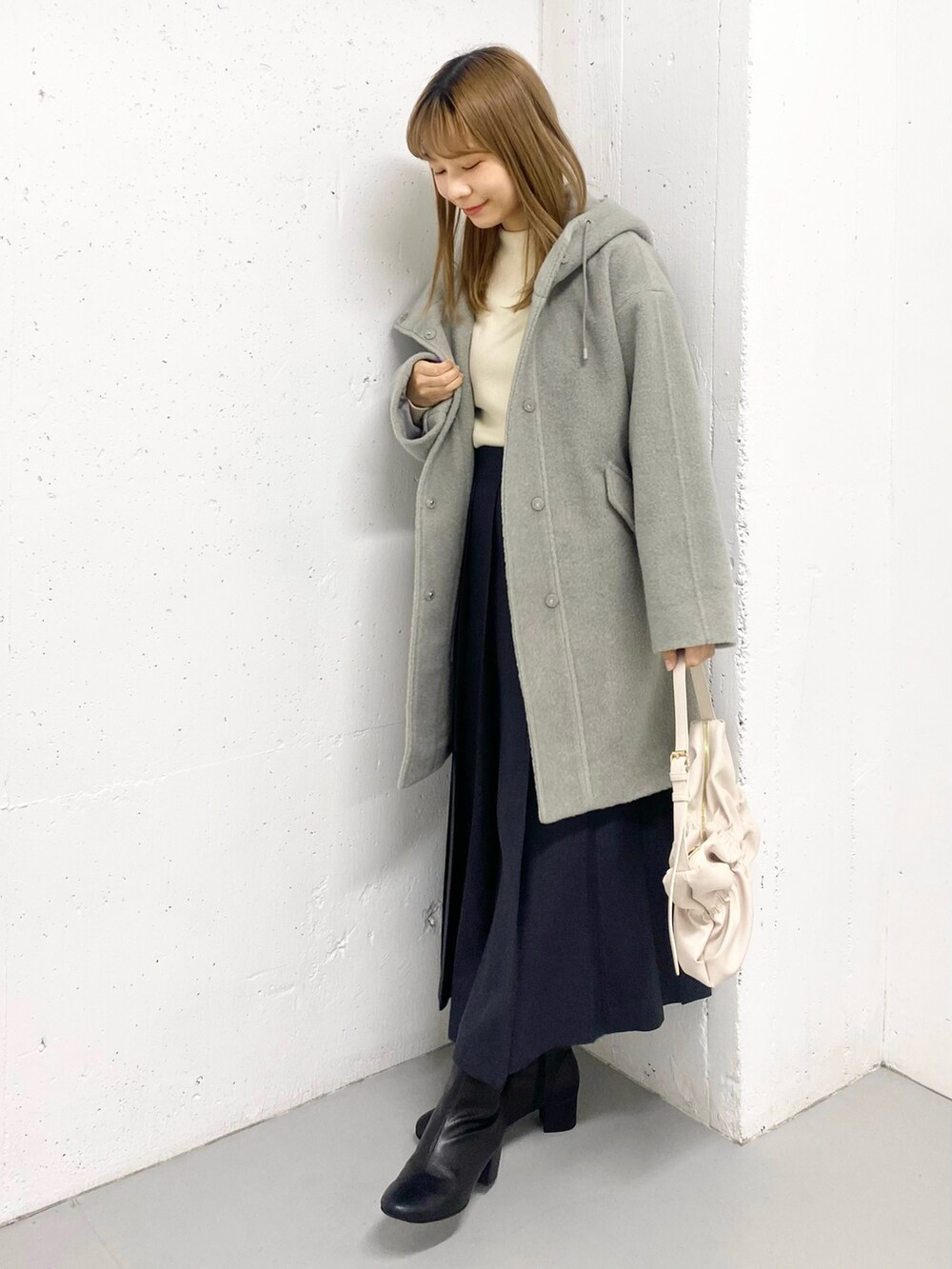 グリーン系のその他アウター、ホワイト系のニット/セーター、ブラック系のブーツを着用したレディースの冬コーディネートの2枚目の写真