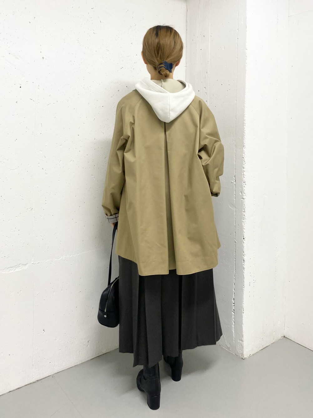 グレー系のスカート、ブラック系のブーツ、ベージュ系のステンカラーコートを着用したレディースの秋コーディネートの5枚目の写真