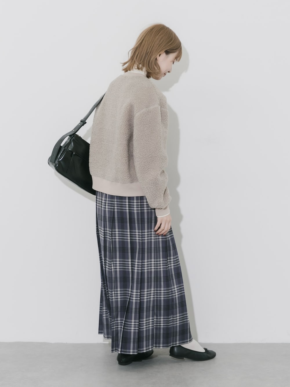 グレー系のスカート、ベージュ系のカーディガン/ボレロ、ブラック系のショルダーバッグを着用したレディースの秋コーディネートの3枚目の写真