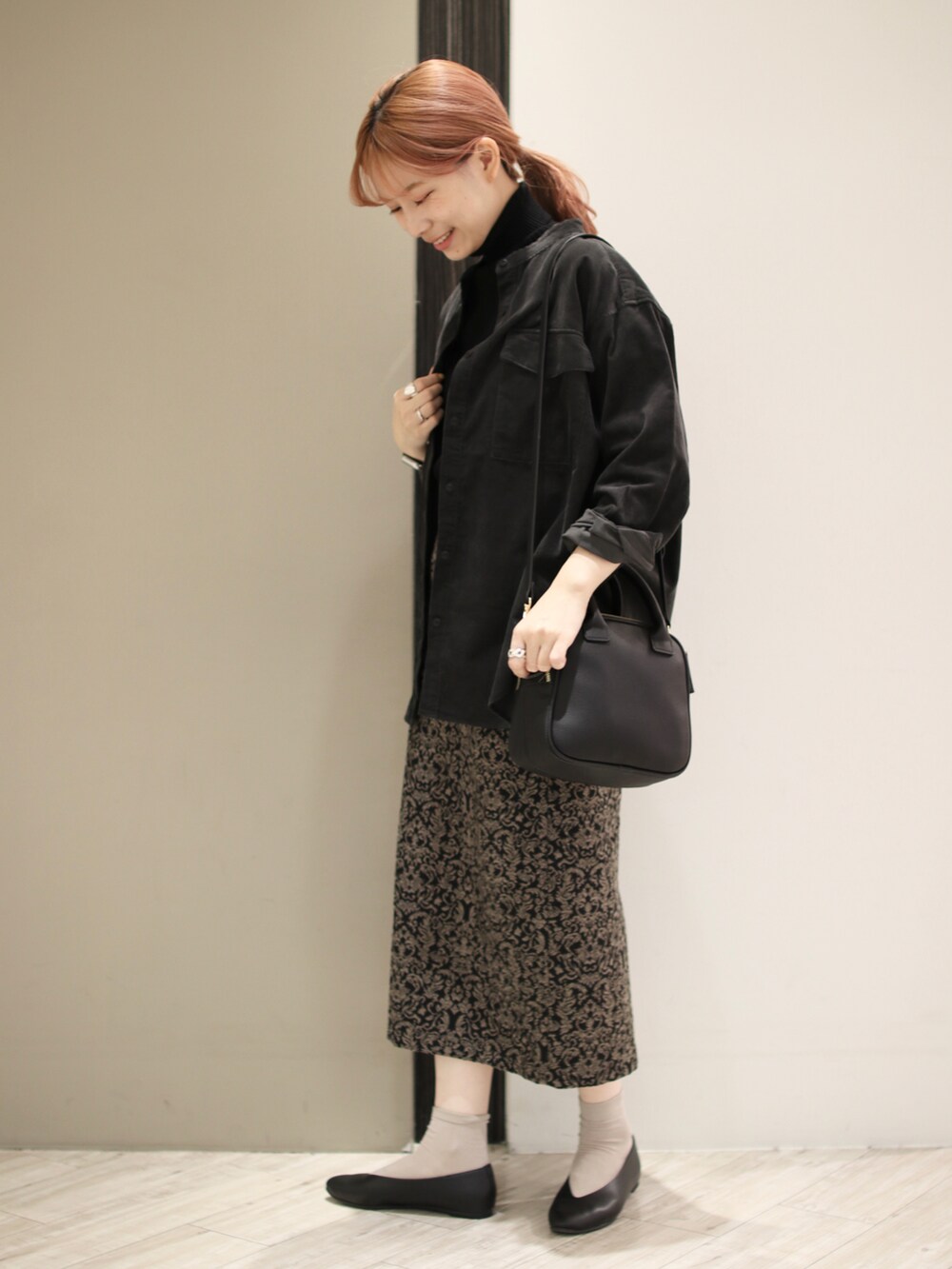 ブラック系のパンプス、ブラック系のショルダーバッグ、ブラック系のスカートを着用したレディースの秋コーディネートの3枚目の写真