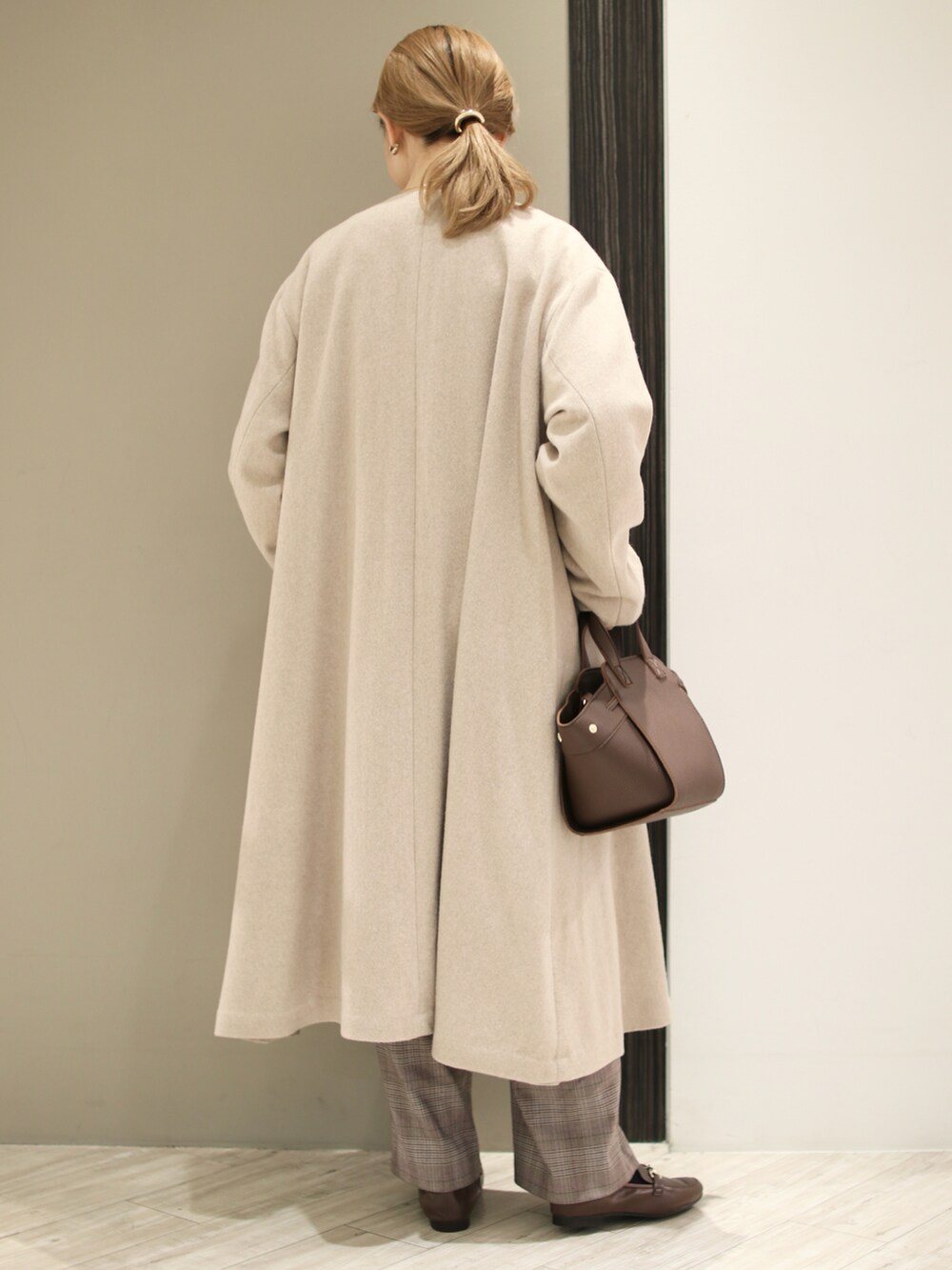 ブラウン系のハンドバッグ、パープル系のスウェット、ベージュ系のその他アウターを着用したレディースの冬コーディネートの4枚目の写真