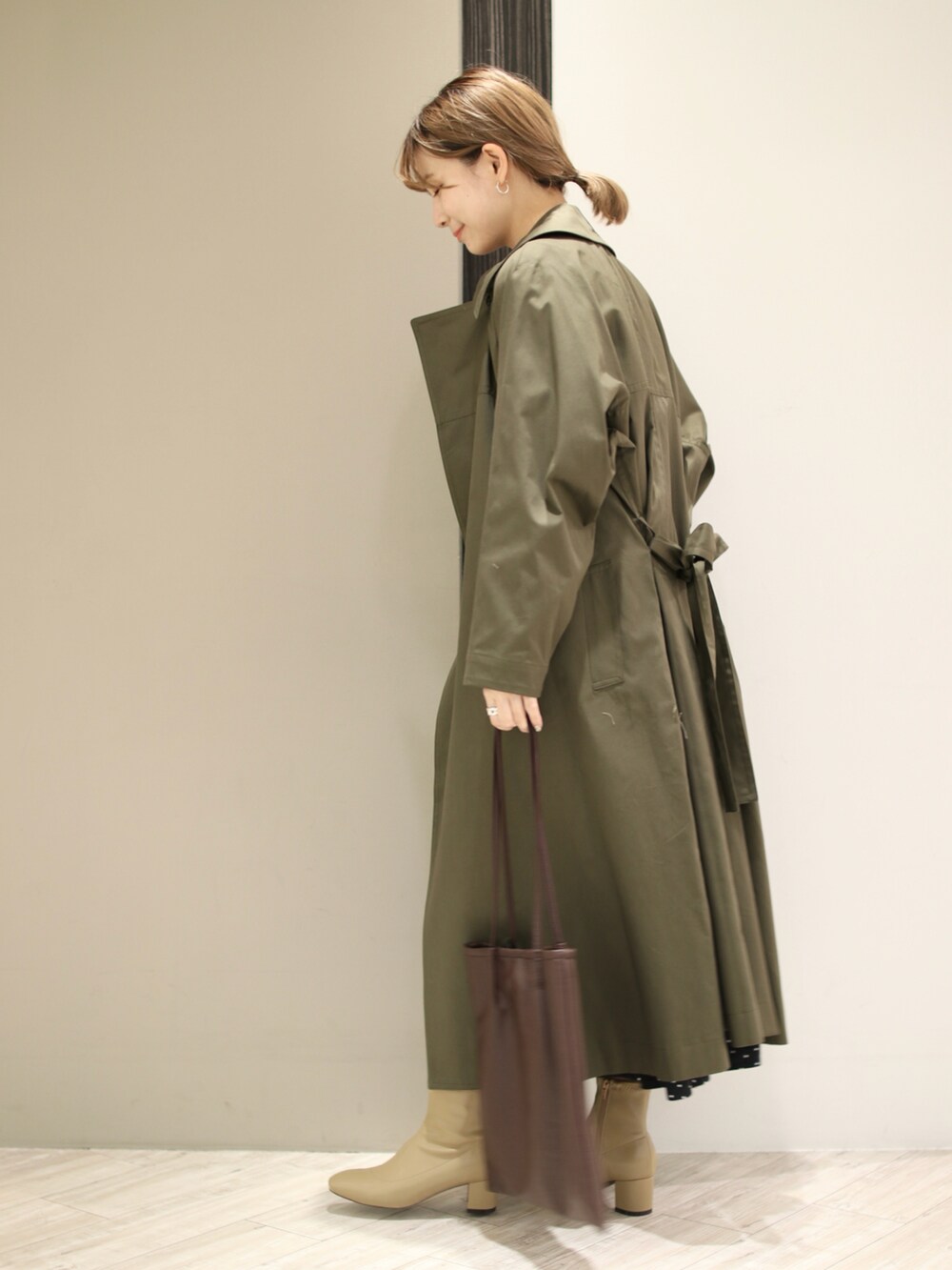 ブラウン系のトートバッグ、ベージュ系のブーツ、ブラック系のワンピースを着用したレディースの冬コーディネートの4枚目の写真