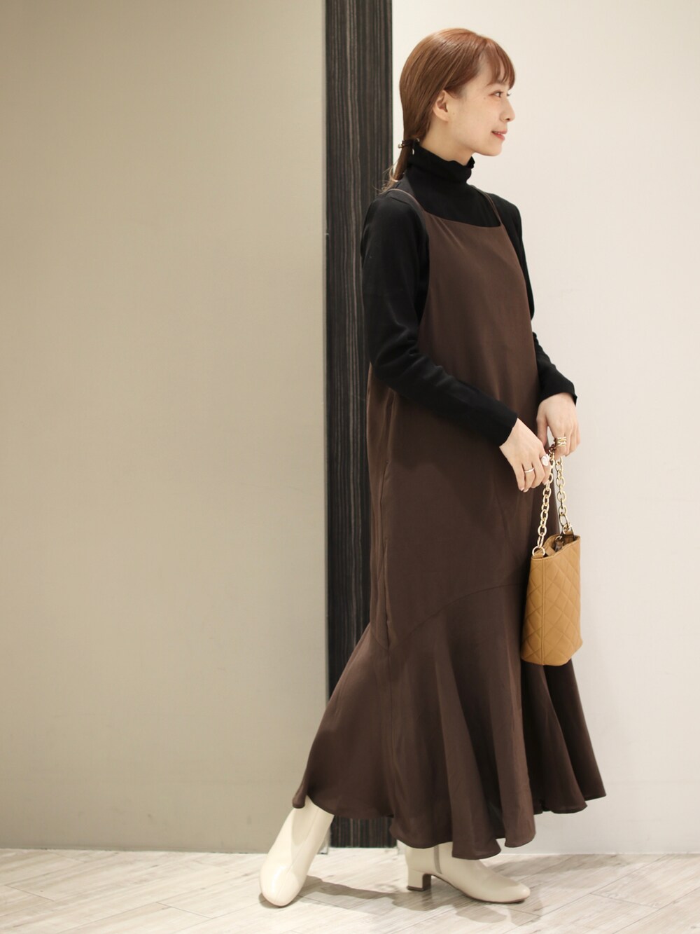 ベージュ系のショルダーバッグ、ベージュ系のブーツ、ブラック系のTシャツ/カットソーを着用したレディースの秋コーディネートの2枚目の写真