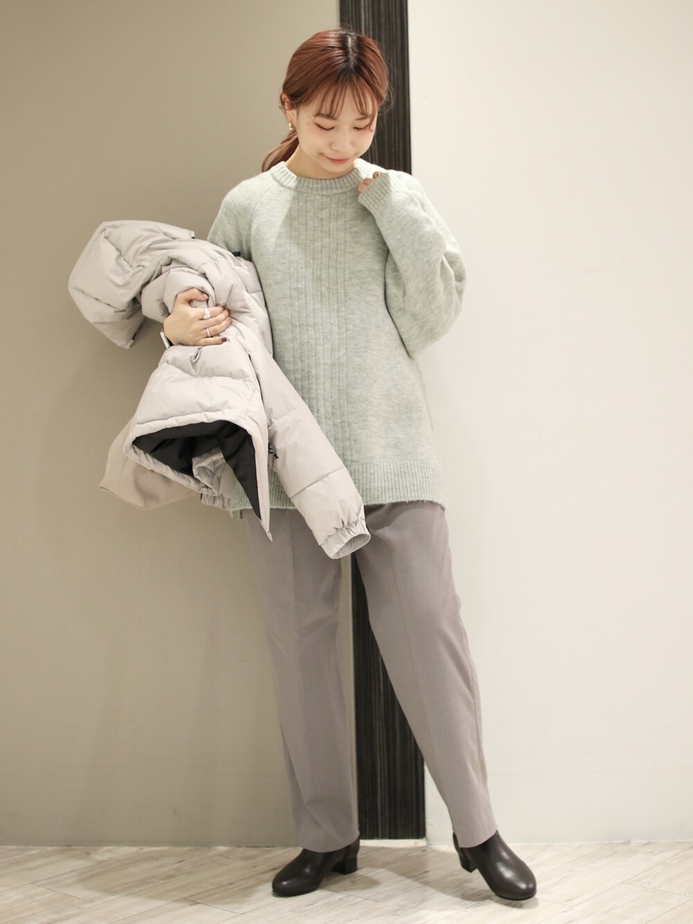 グレー系のその他パンツ、ブラウン系のブーツ、グリーン系のニット/セーターを着用したレディースの冬コーディネートの2枚目の写真