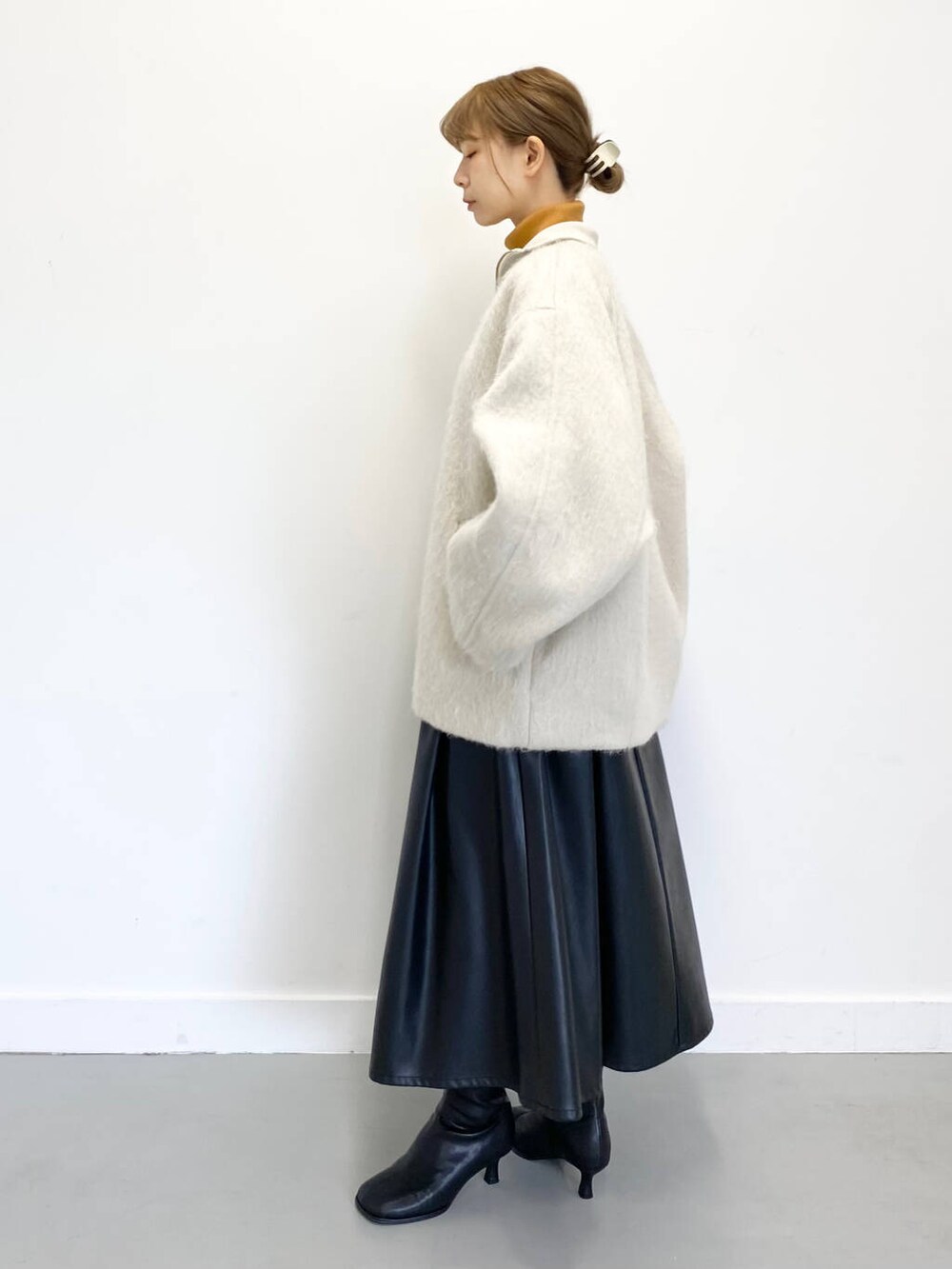 イエロー系のニット/セーター、ブラック系のショルダーバッグ、ブラック系のブーツを着用したレディースの冬コーディネートの4枚目の写真