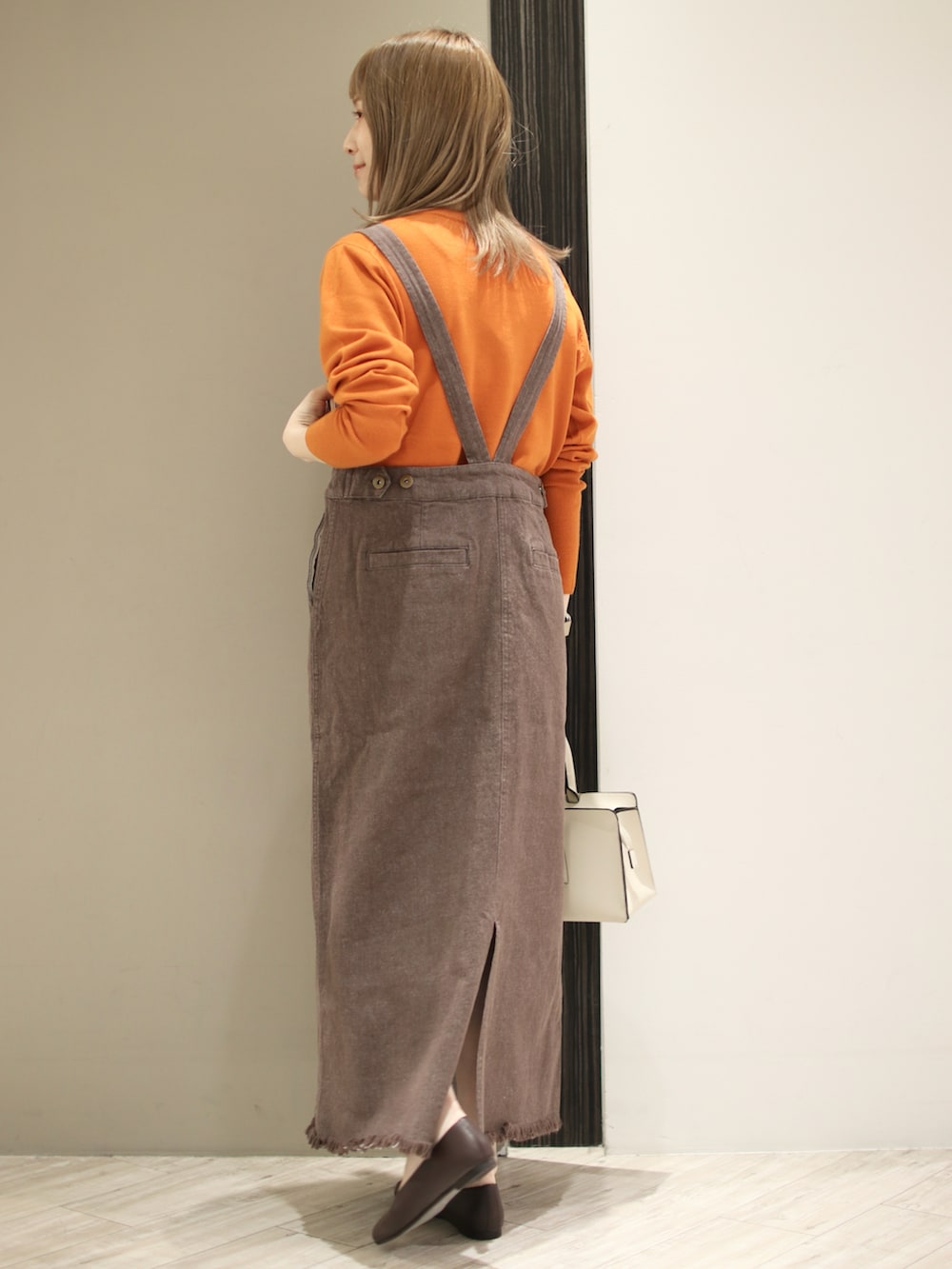 グレー系のトートバッグ、ブラウン系のサロペット/オーバーオール、オレンジ系のニット/セーターを着用したレディースの秋コーディネートの2枚目の写真