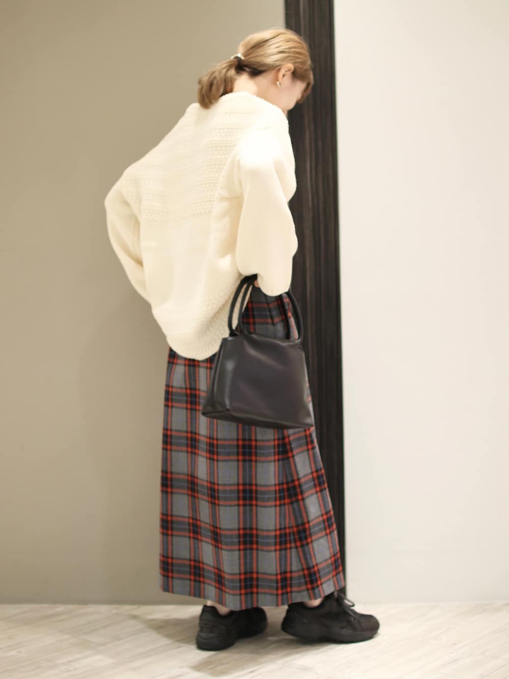ホワイト系のニット/セーター、グレー系のスカート、ブラック系のハンドバッグを着用したレディースの秋コーディネートの4枚目の写真